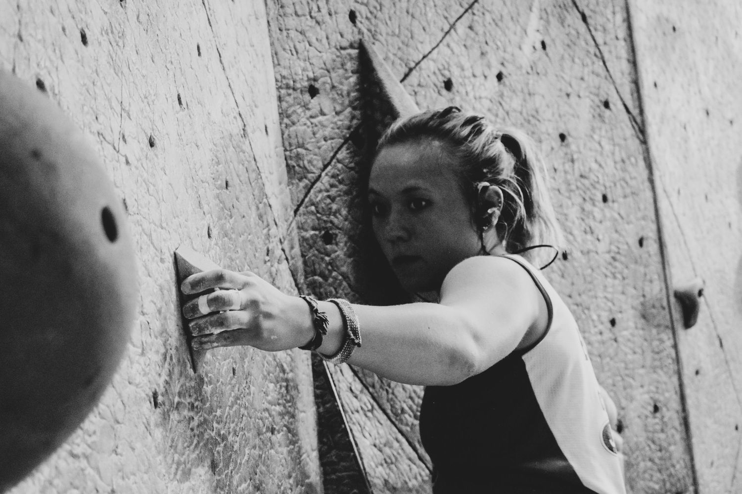 Profile view of a climber making a challenging move on an indoor climbing wall.