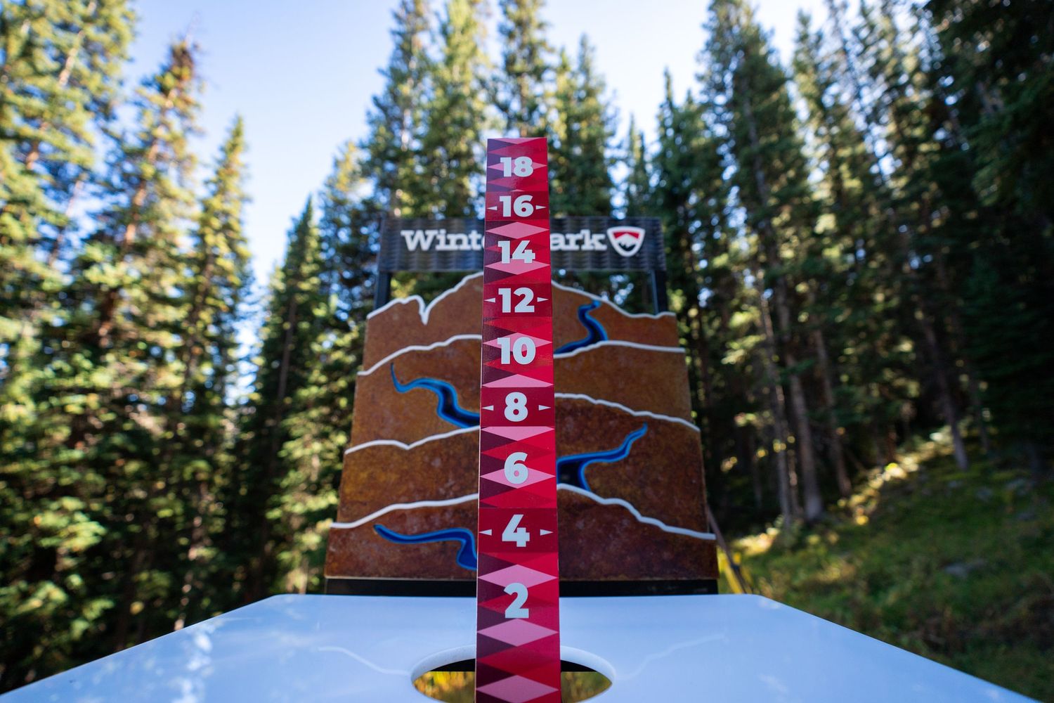 Wooden trail map marker with elevation numbers against forest backdrop.