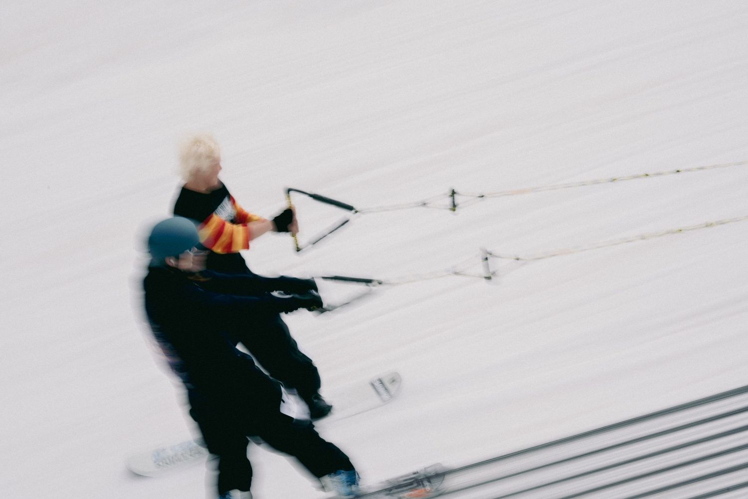 Two skiers in motion blur racing down a snowy slope during a winter competition.