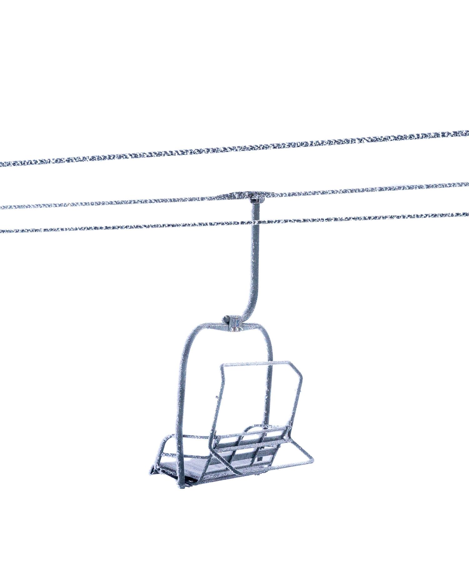 Empty ski lift chair suspended on cables against a white background.