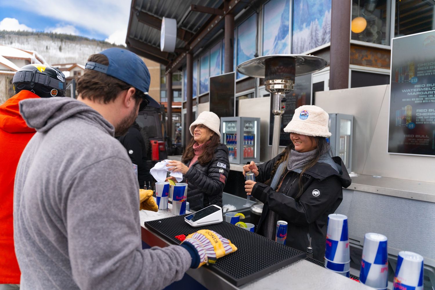 People getting refreshments at outdoor ski resort concession counter.