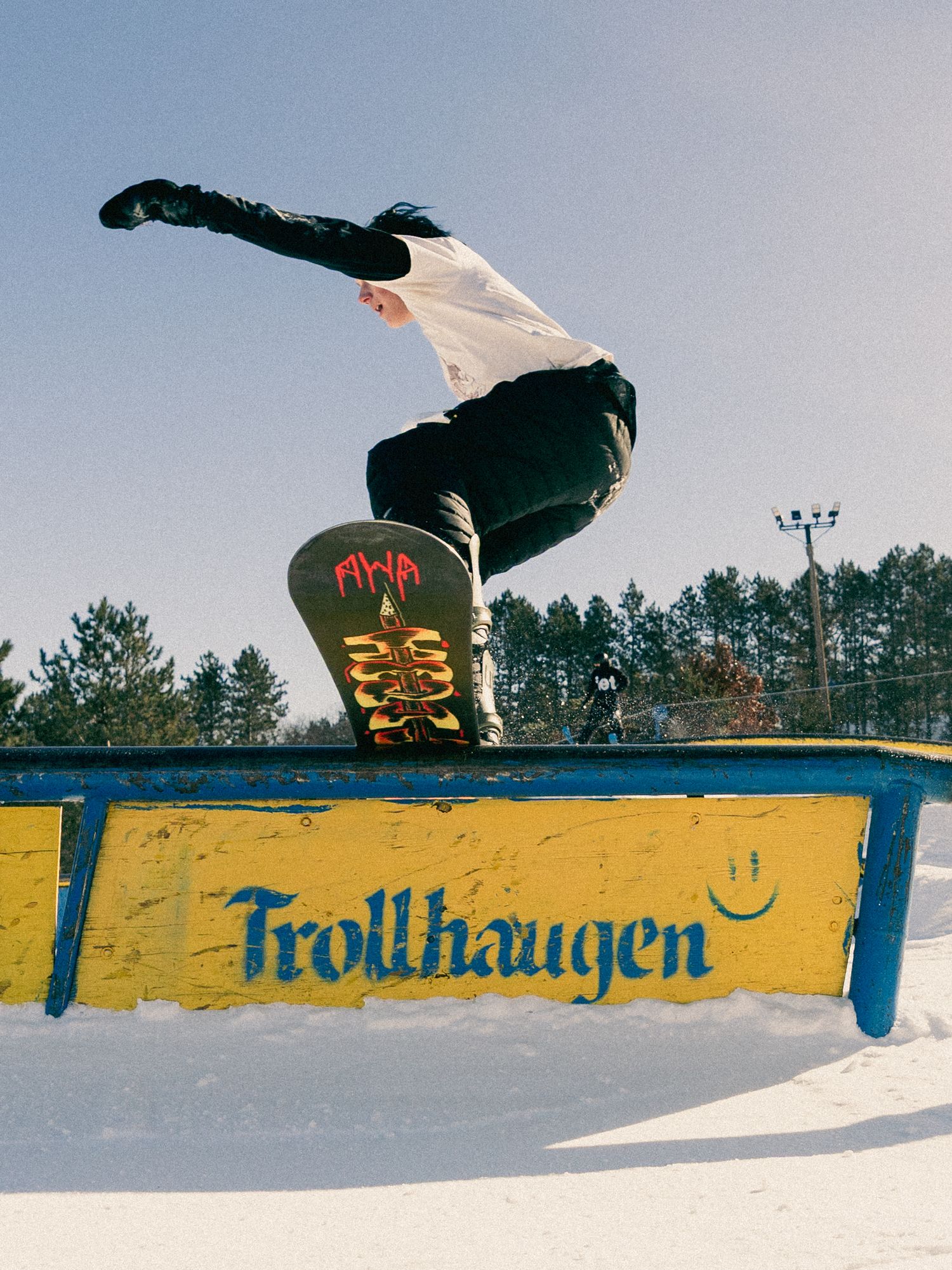 Snowboarder performing a rail grind trick at Trollhaugen ski resort on a sunny winter day.