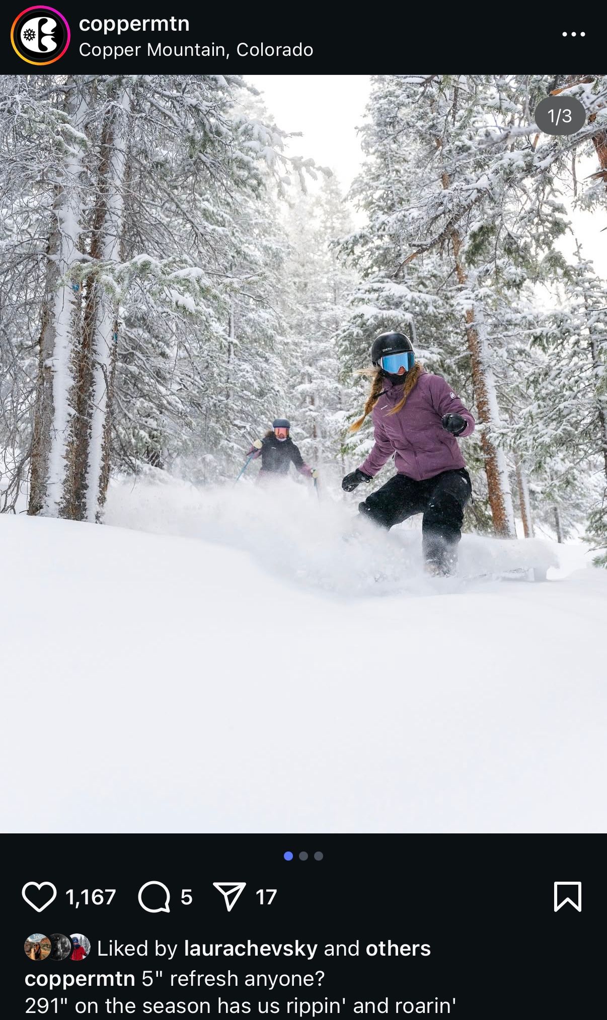Skiers carving through fresh powder snow on a tree-lined slope at Copper Mountain, Colorado.