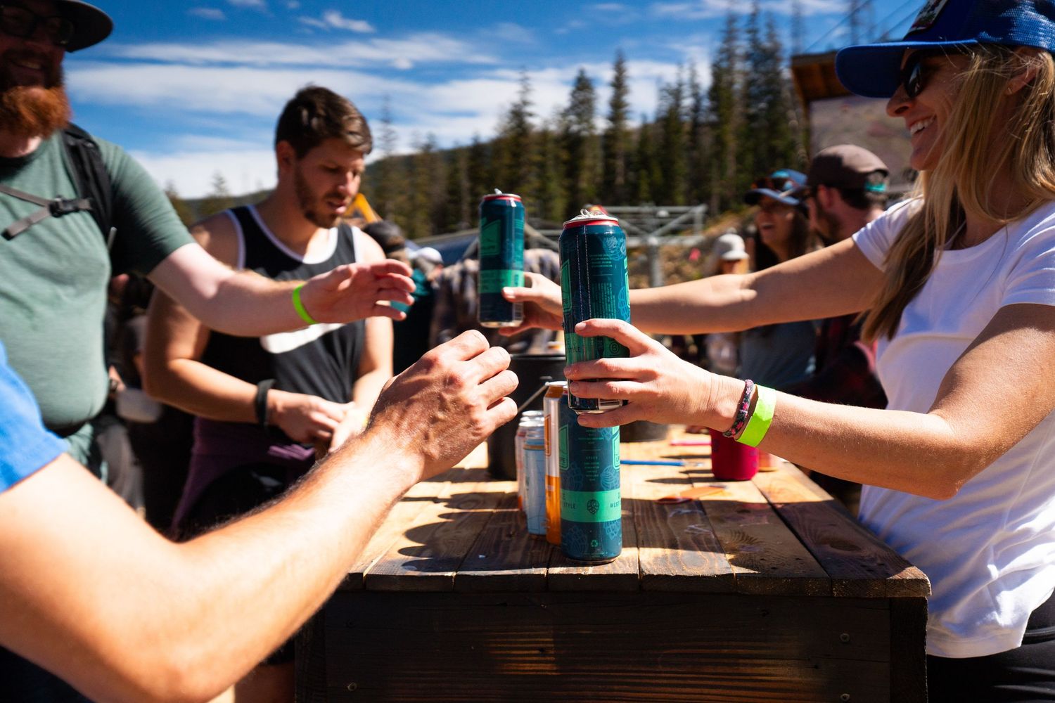 Group of friends toasting with colorful insulated drink containers on a sunny mountain day.