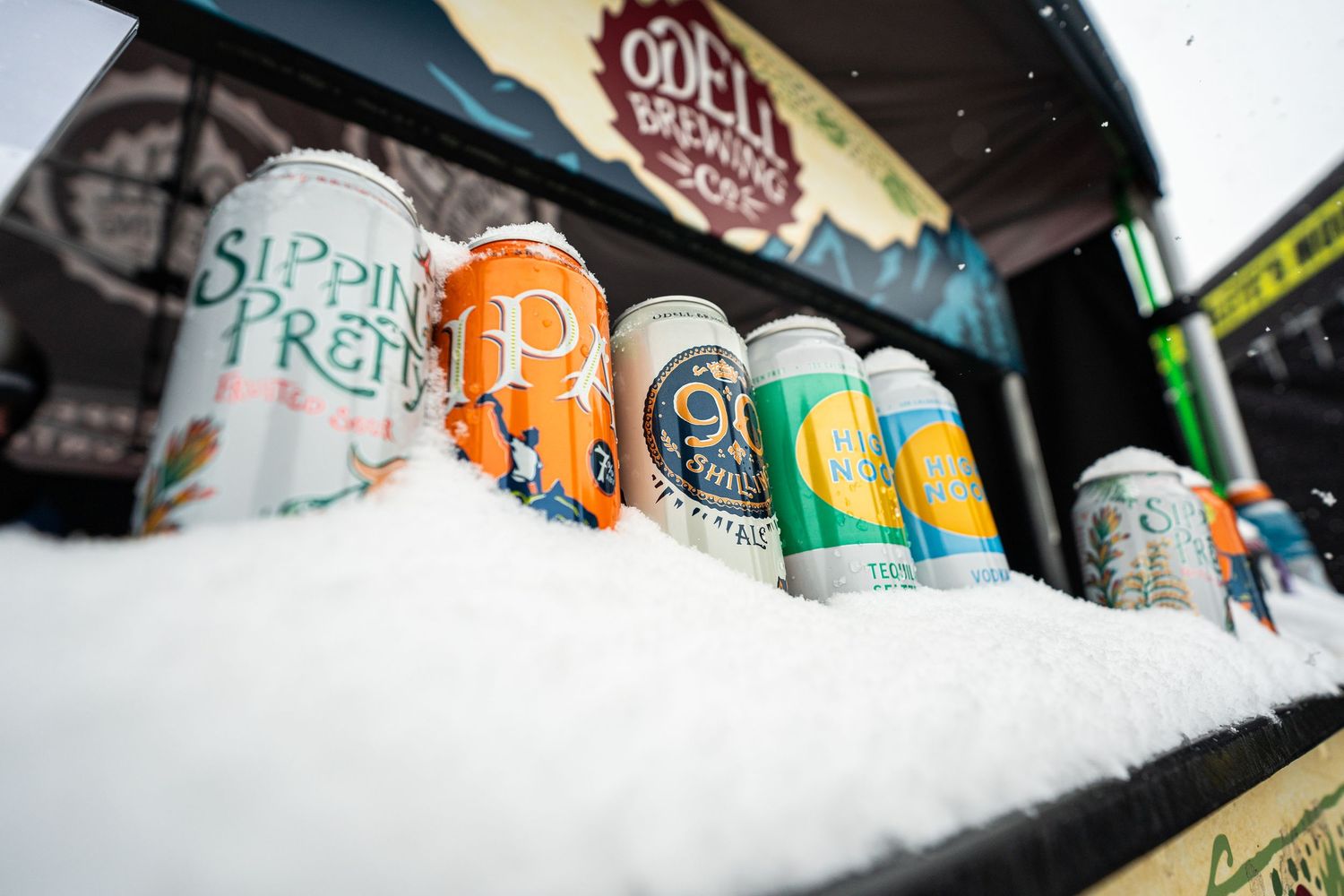 Colorful craft beer cans arranged in snow displaying various brewery labels.