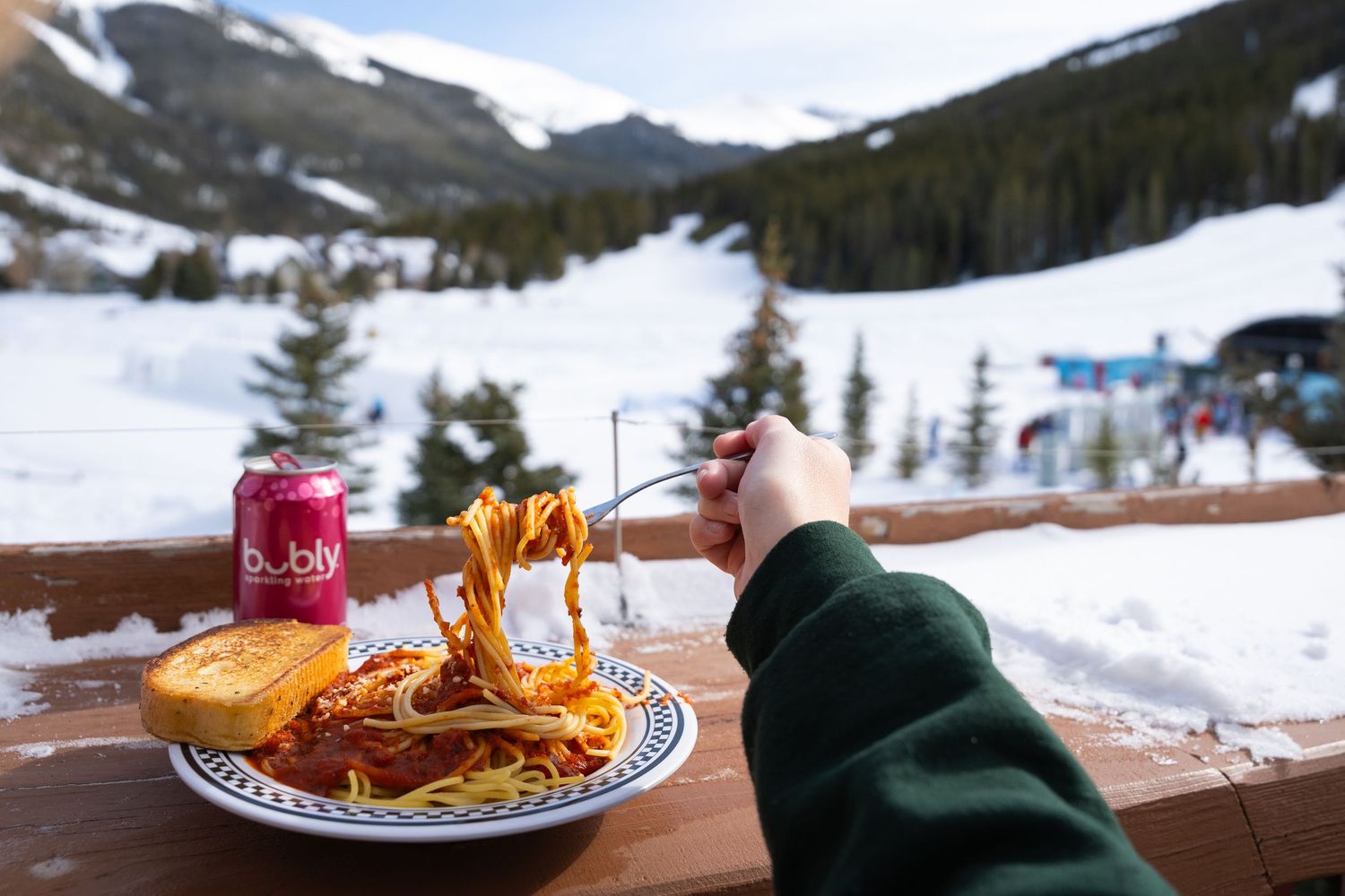Spaghetti meal with snowy mountain ski resort view from outdoor dining deck.