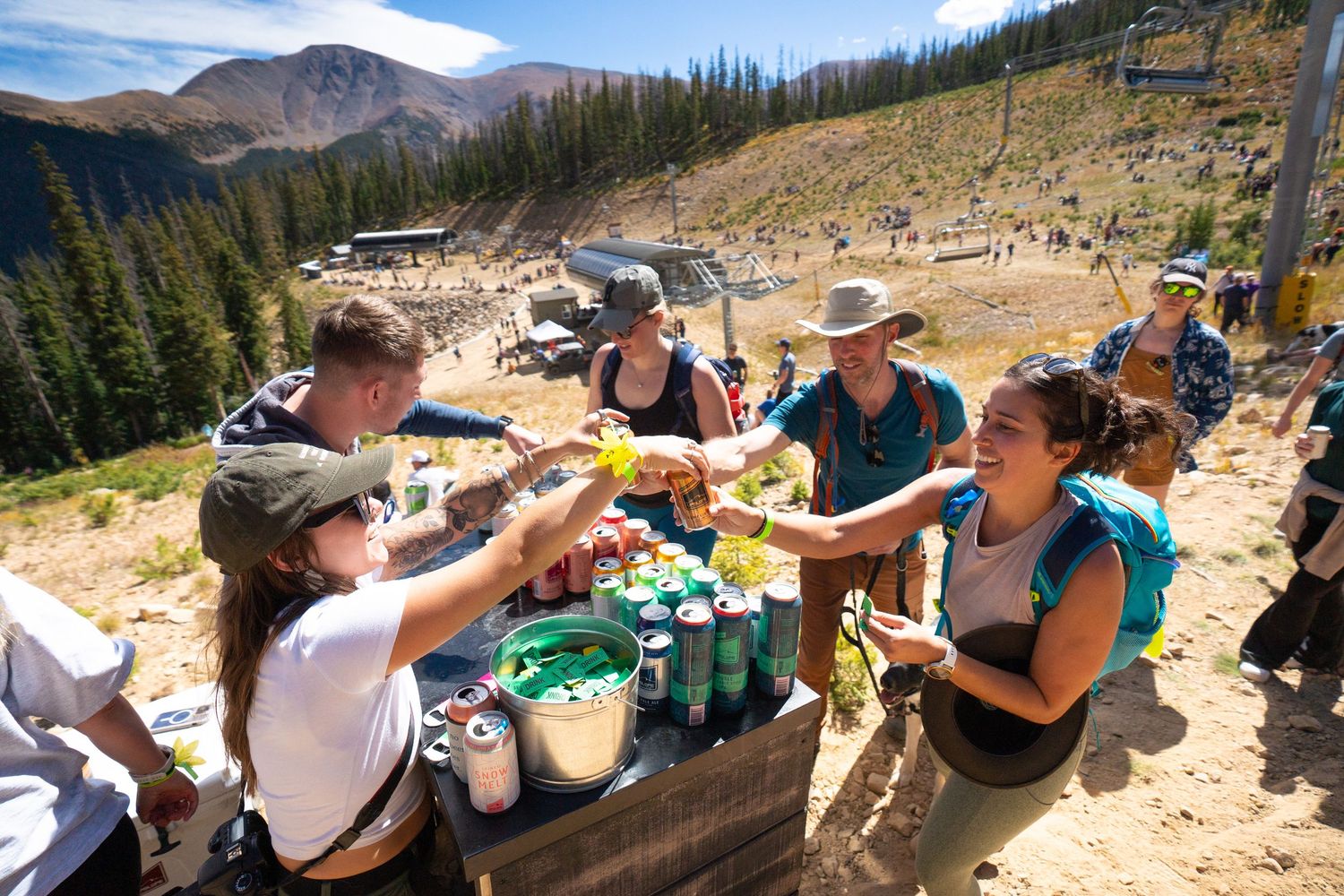 Friends sharing drinks and snacks at an outdoor mountain gathering.