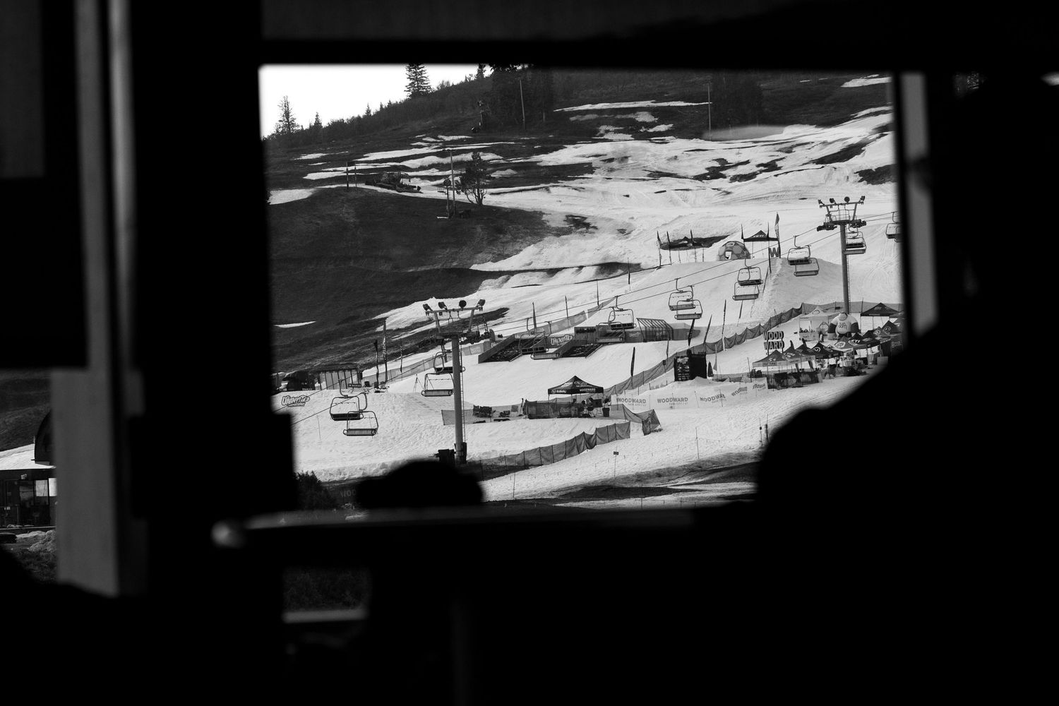Black and white aerial view of ski resort terrain park seen through window frame.