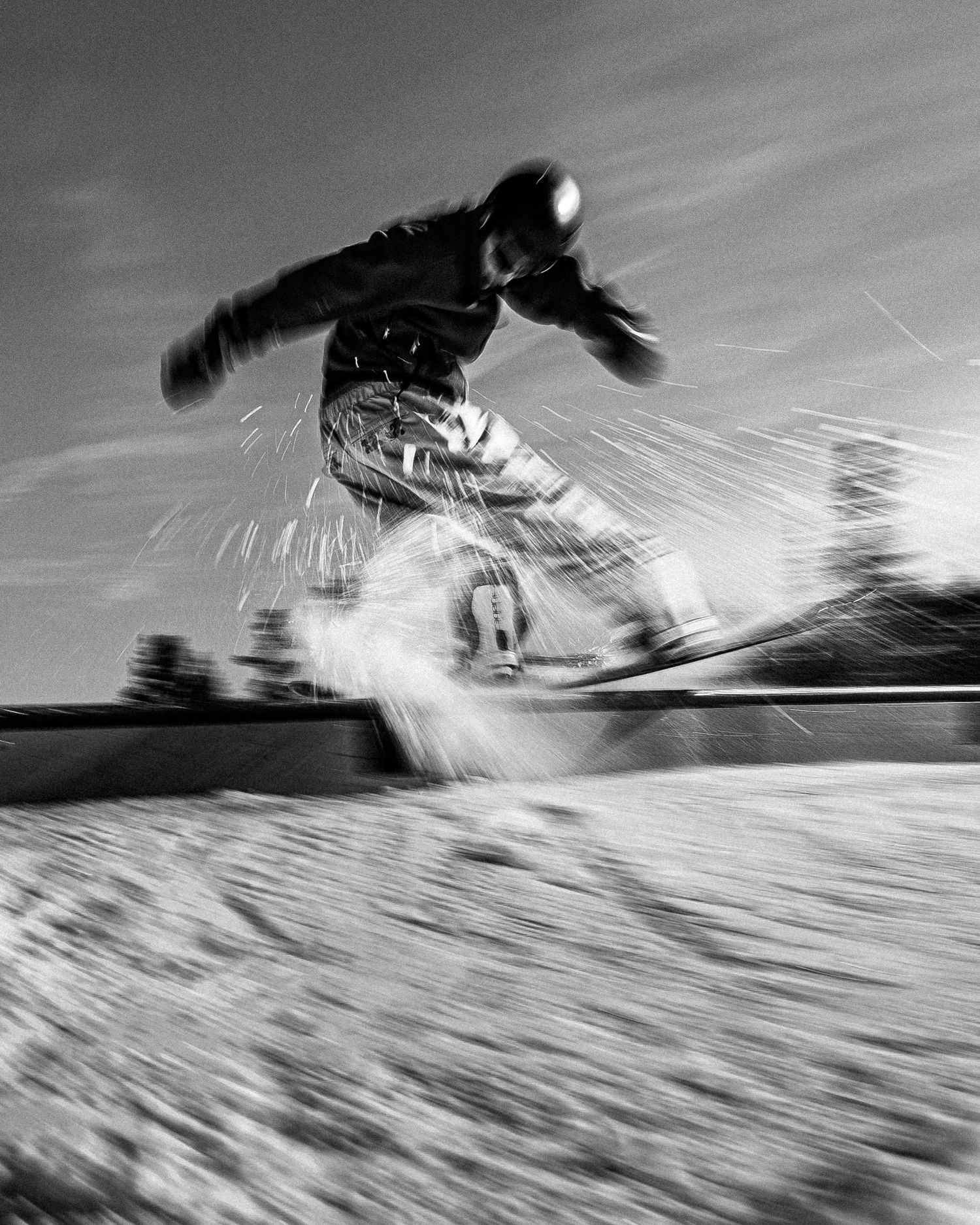 Dynamic black and white action shot of snowboarder launching off jump with snow spray.