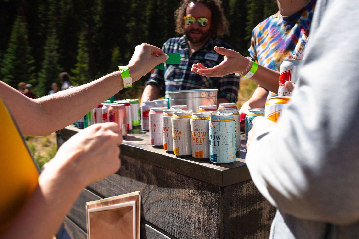 Various drinks and beverages being shared on rustic wooden surface outdoors.