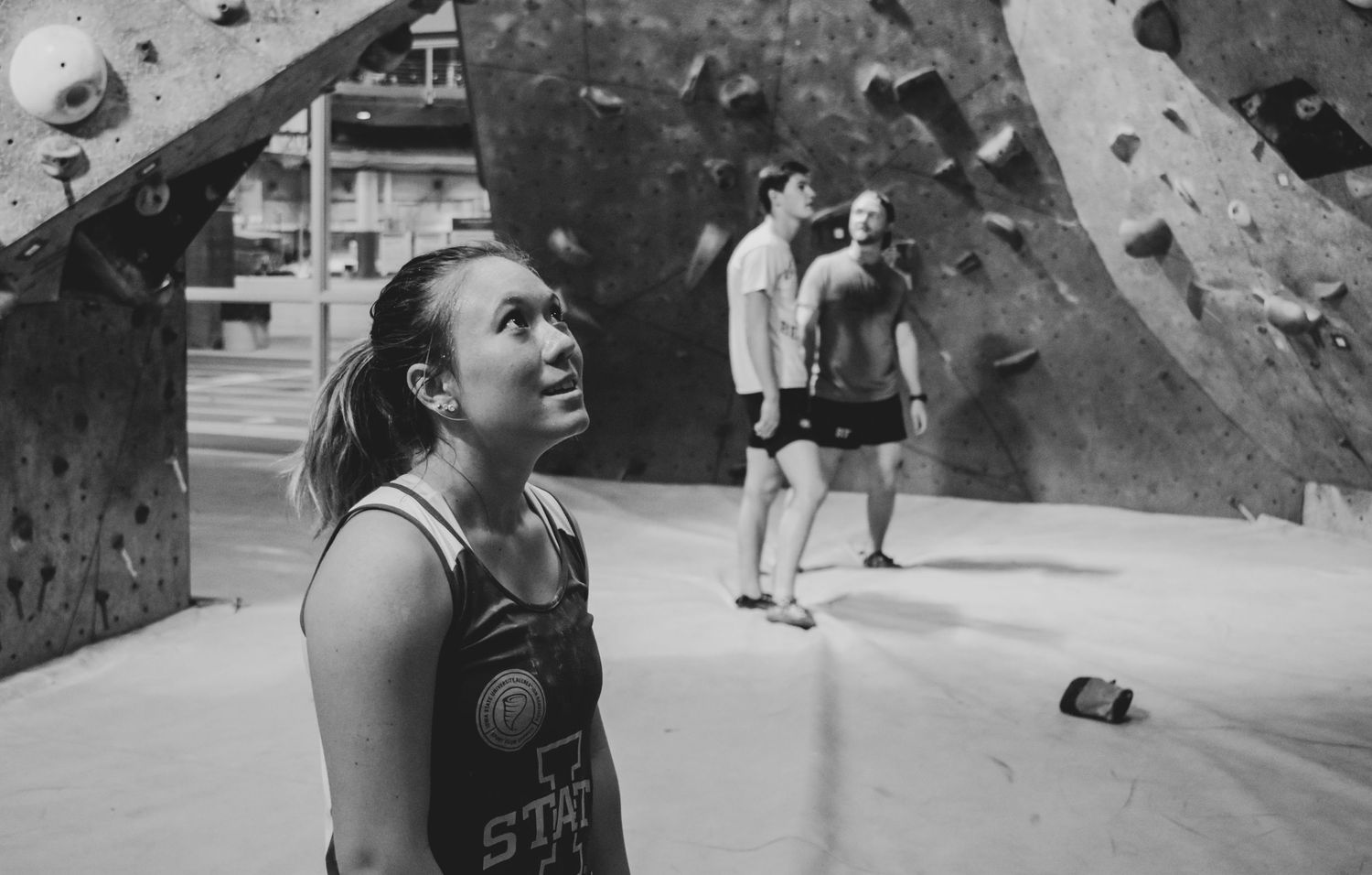 Climber looks up at indoor climbing wall while preparing for ascent.