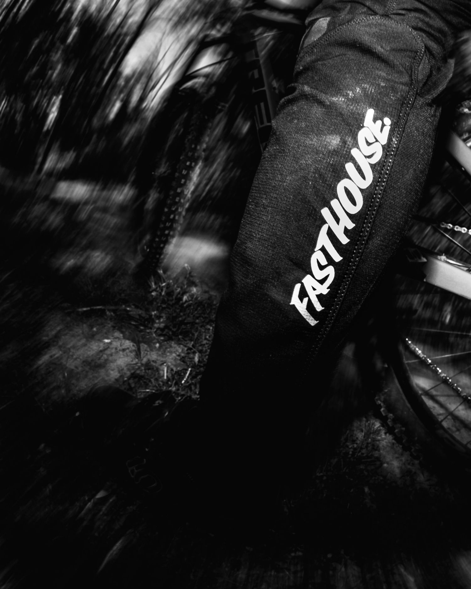 A black and white photo showing a Fasthouse brand logo on black apparel in low-light conditions.