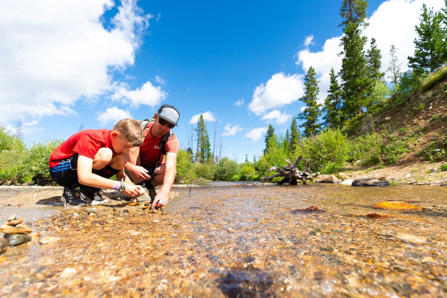 Person drinking from mountain stream while taking break from outdoor activities.