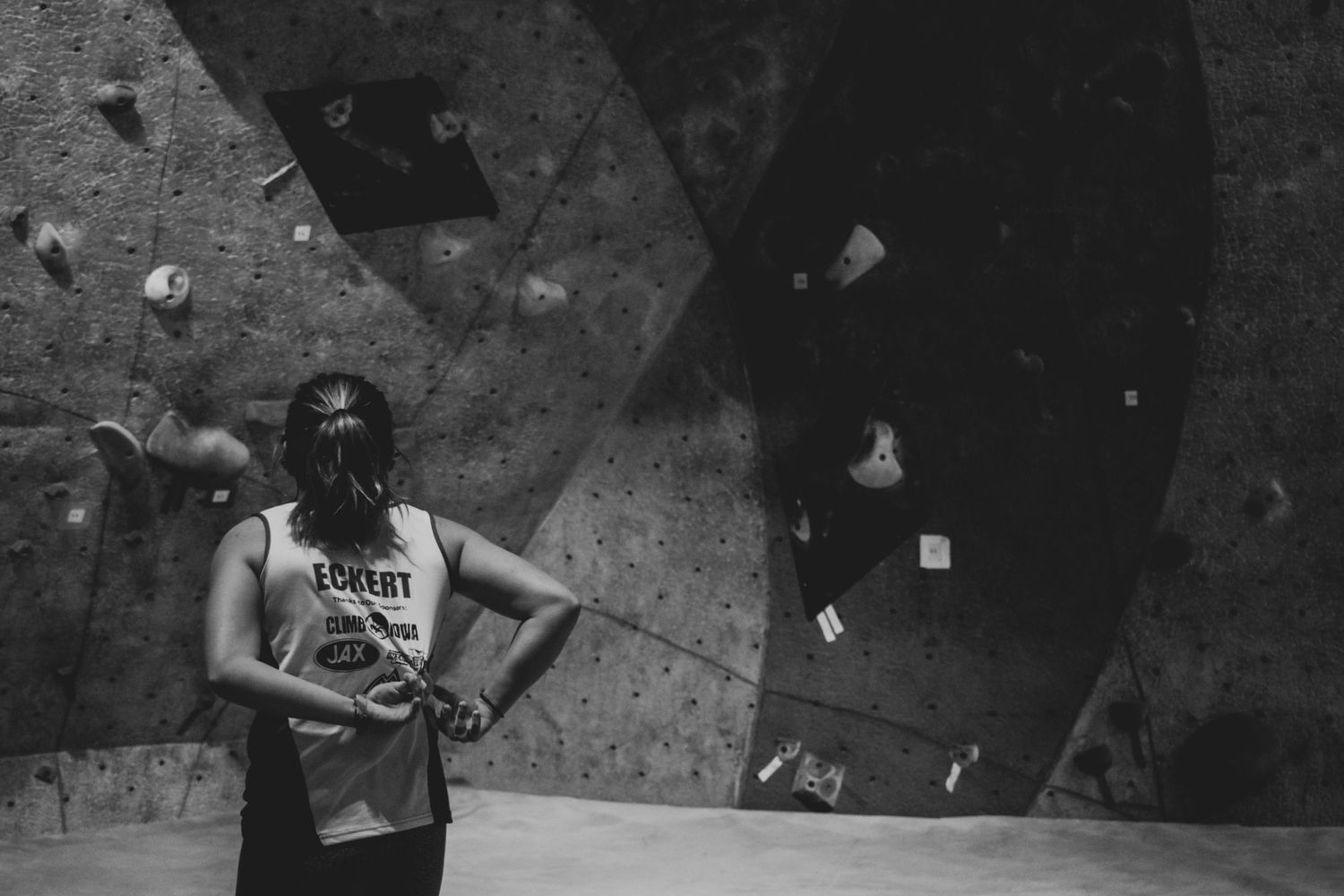 Indoor climbing wall with textured holds and dramatic lighting in black and white.