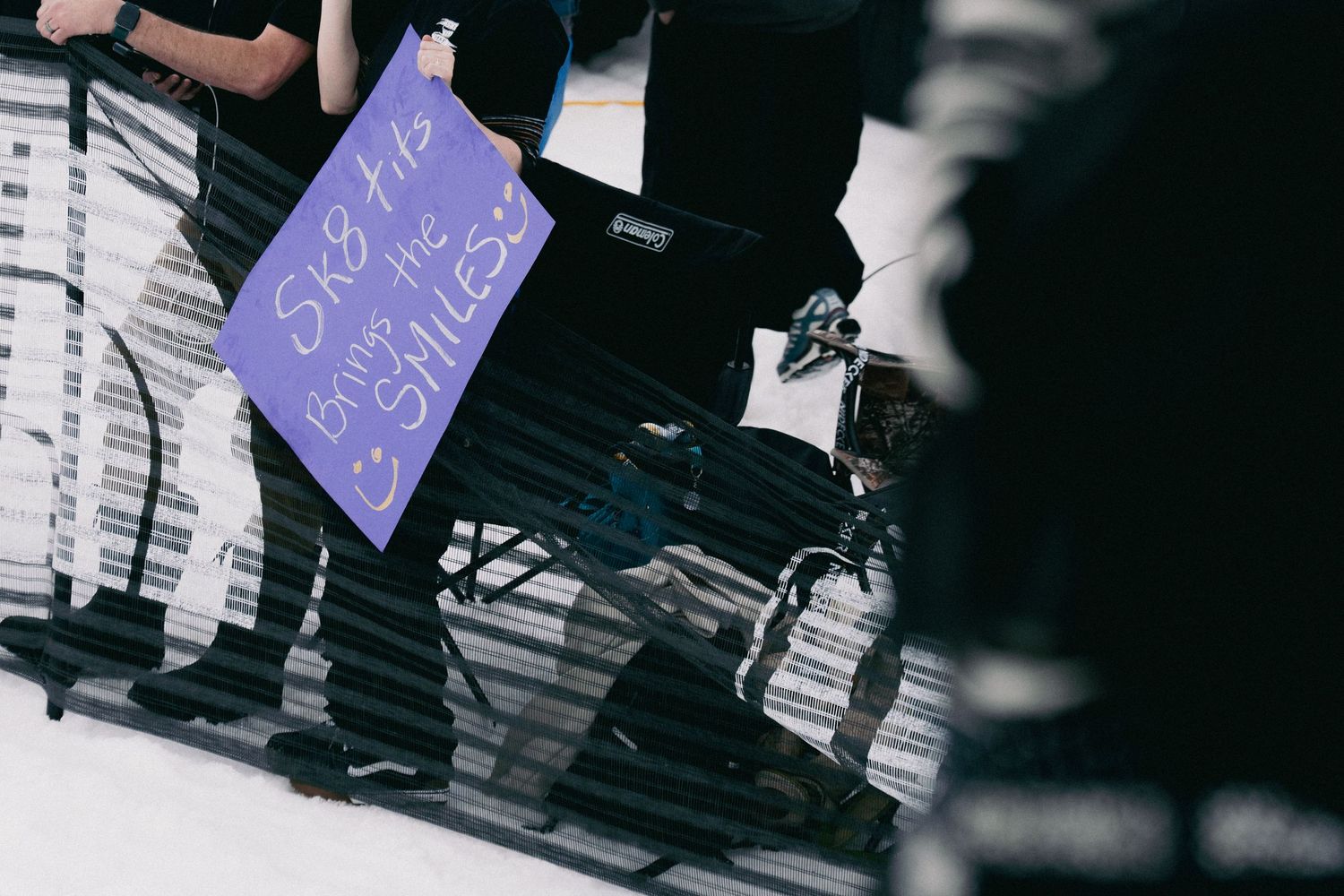 A purple fan sign reading 'Skate for the Smiles' held up at a skating event.