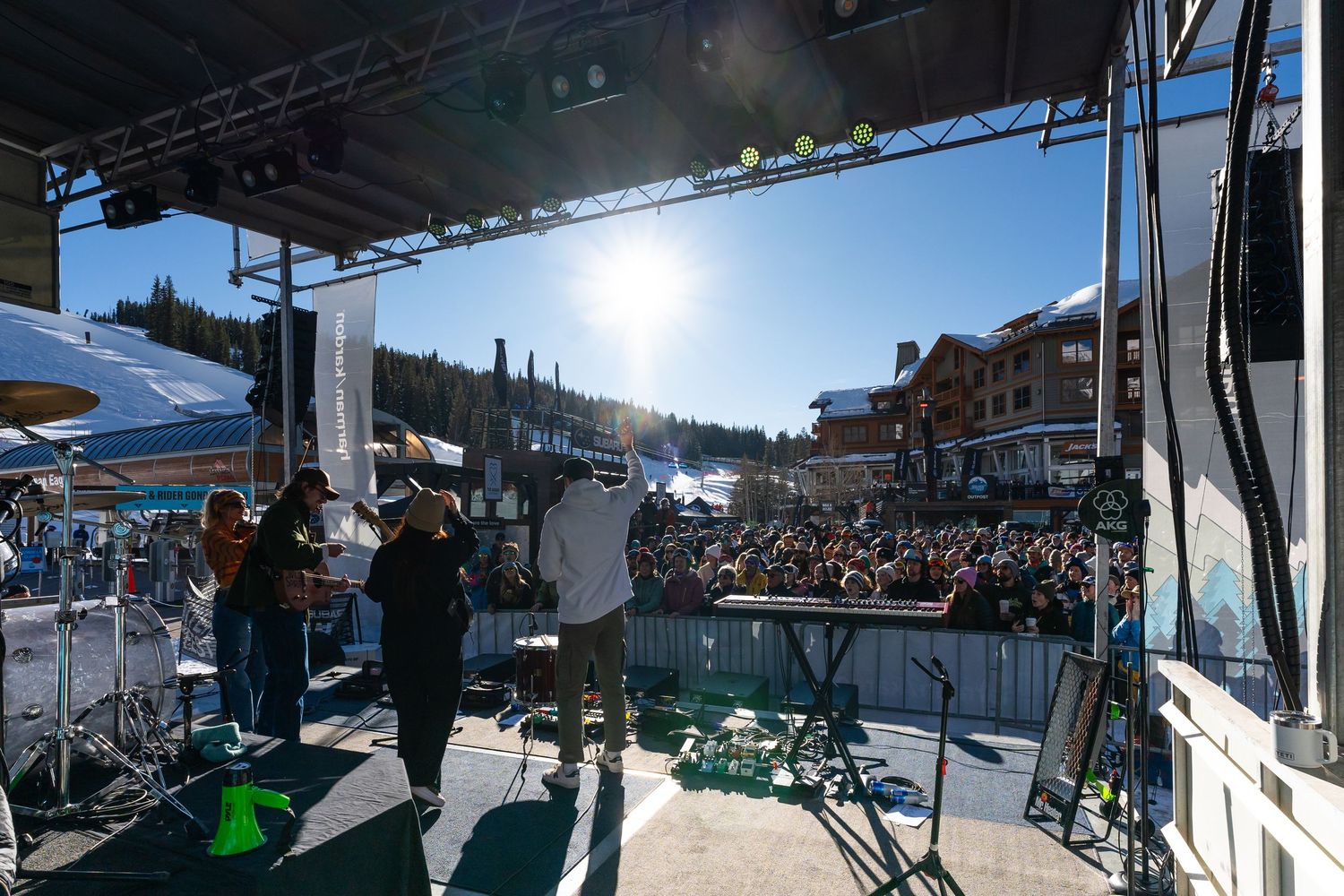 Outdoor concert stage setup with crowd gathering at ski resort base.