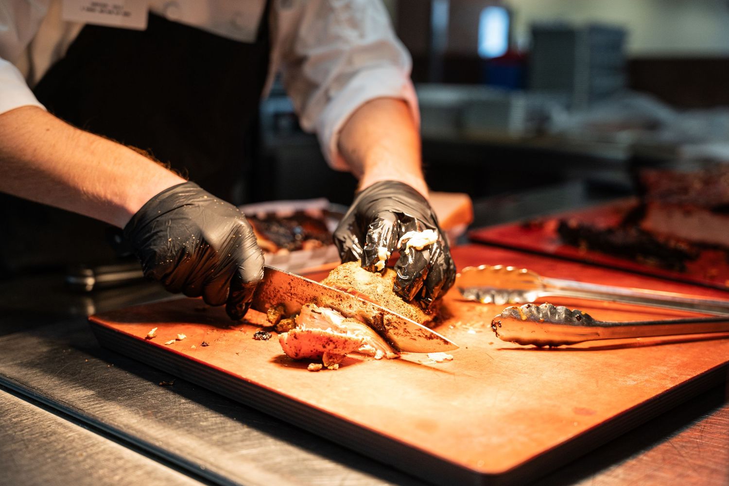 Close-up of hands preparing fresh seafood on orange cutting board in commercial kitchen.