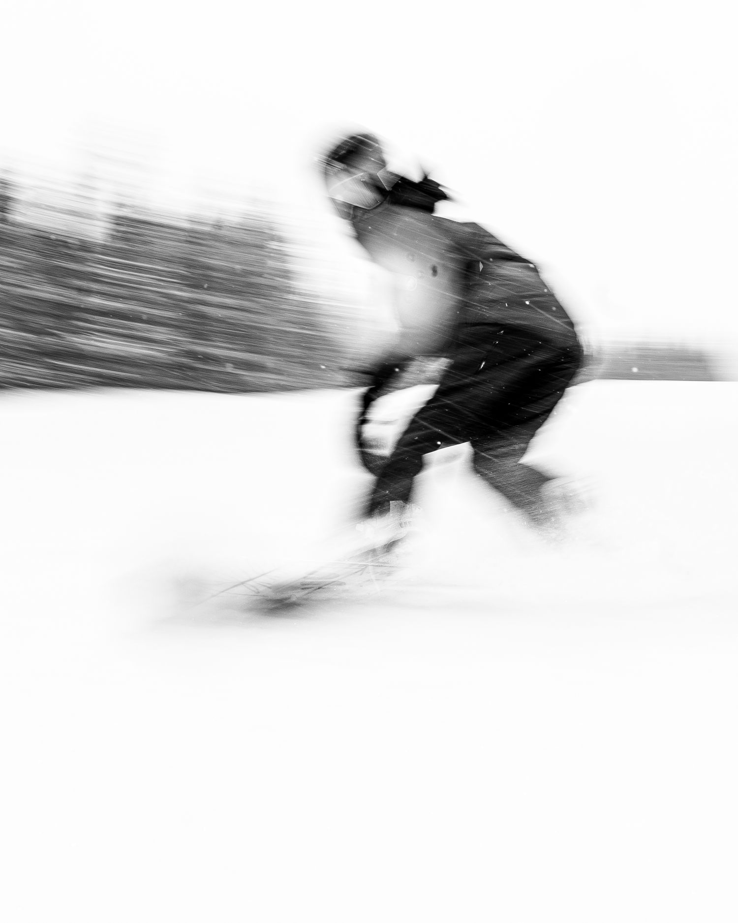 Motion blur black and white photo of snowboarder in action.