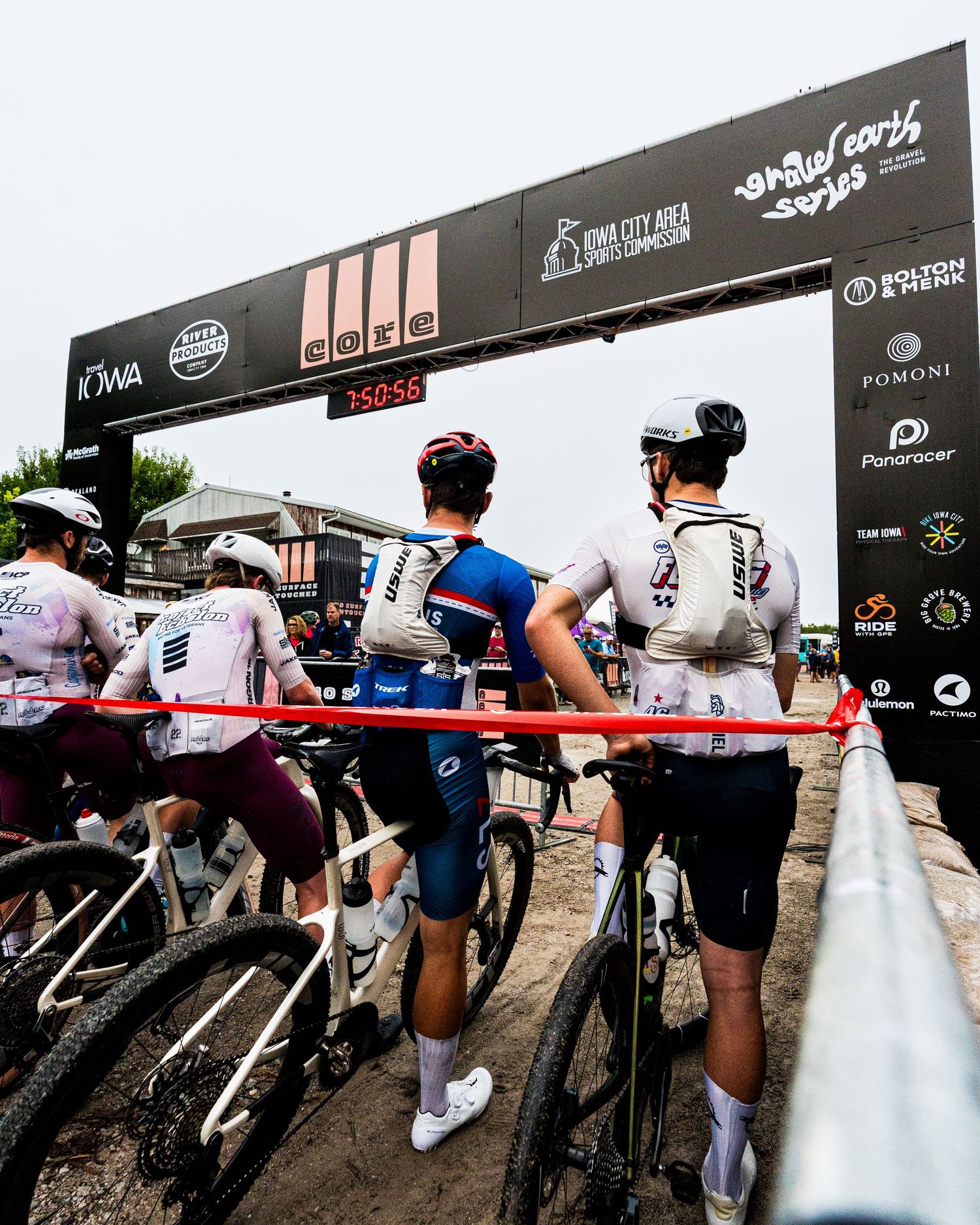 Cyclists line up at the starting gate of the Iowa City gravel bike race, ready to compete.