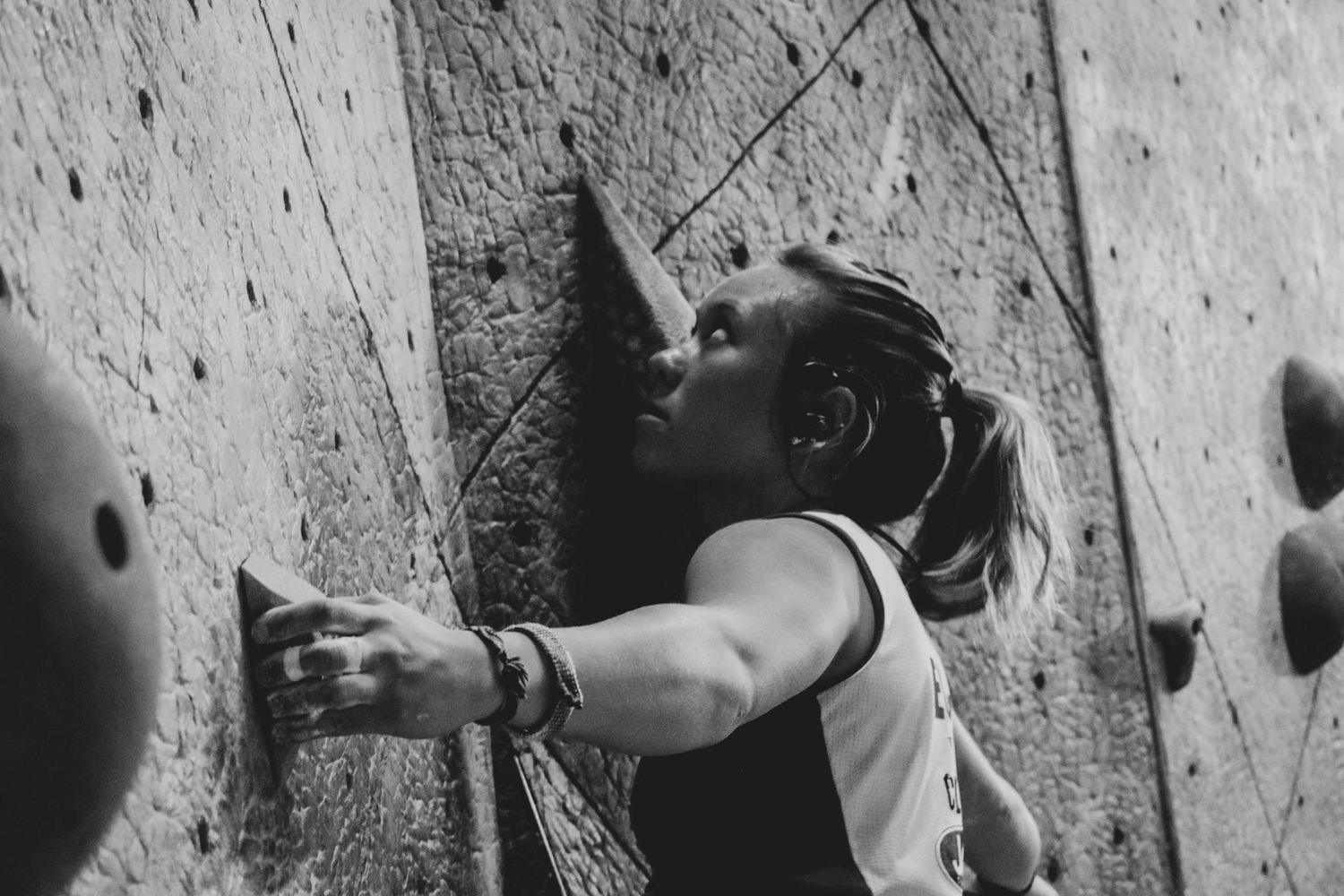 Dynamic shot of a climber stretching to reach the next hold on an indoor wall.