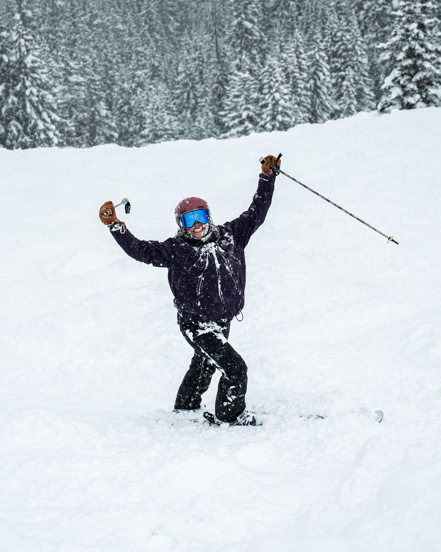 Snowboarder celebrating with arms raised in excitement on snowy mountain slope.