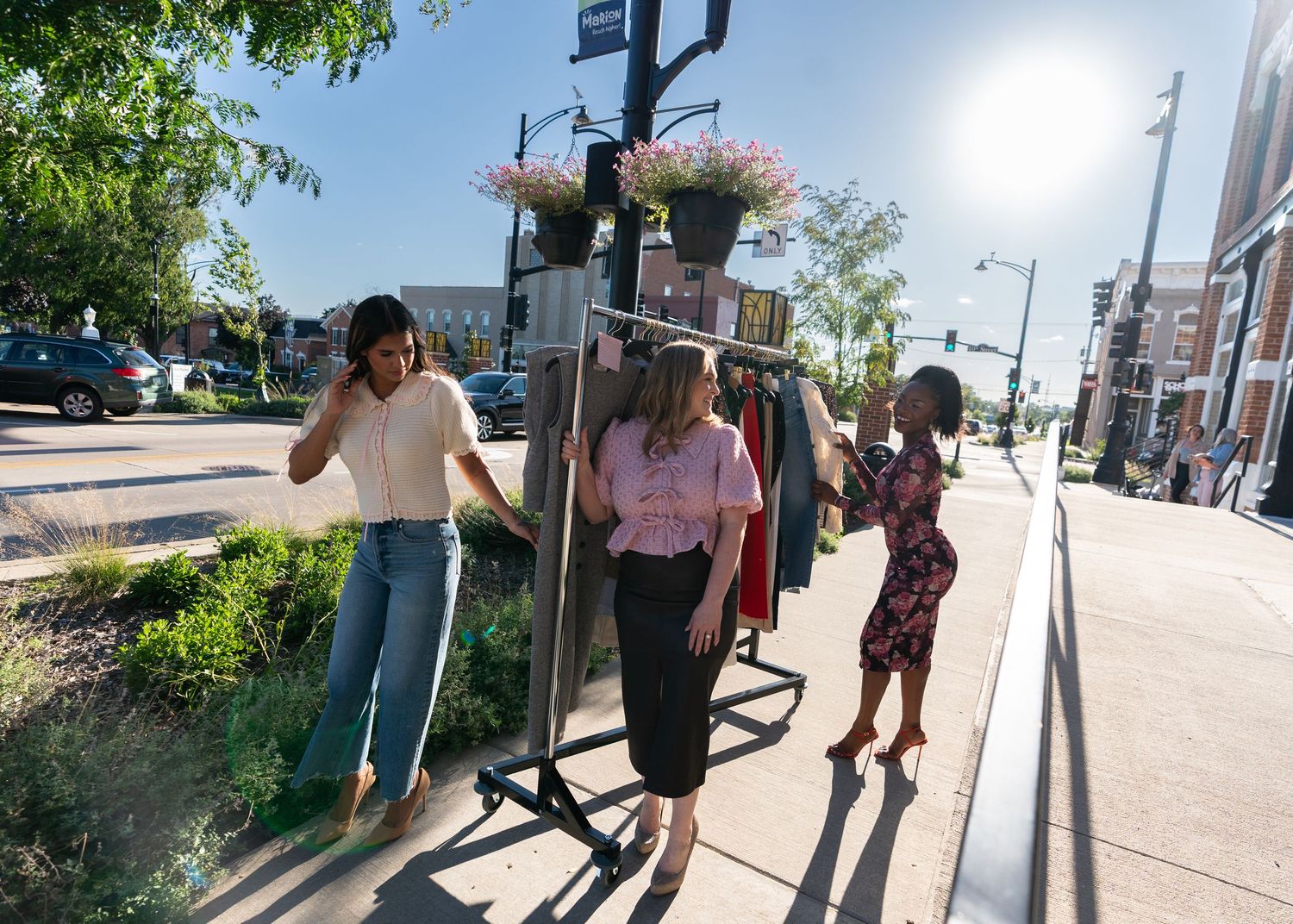 A motion-blurred sequence of people walking on a sunny sidewalk casts long shadows during a summer day.