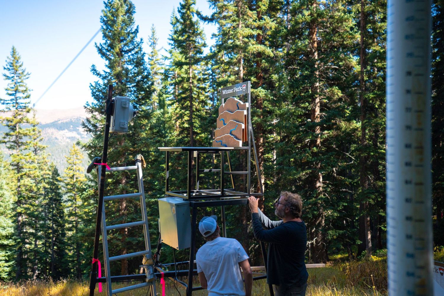 People setting up trail markers in mountain forest clearing.