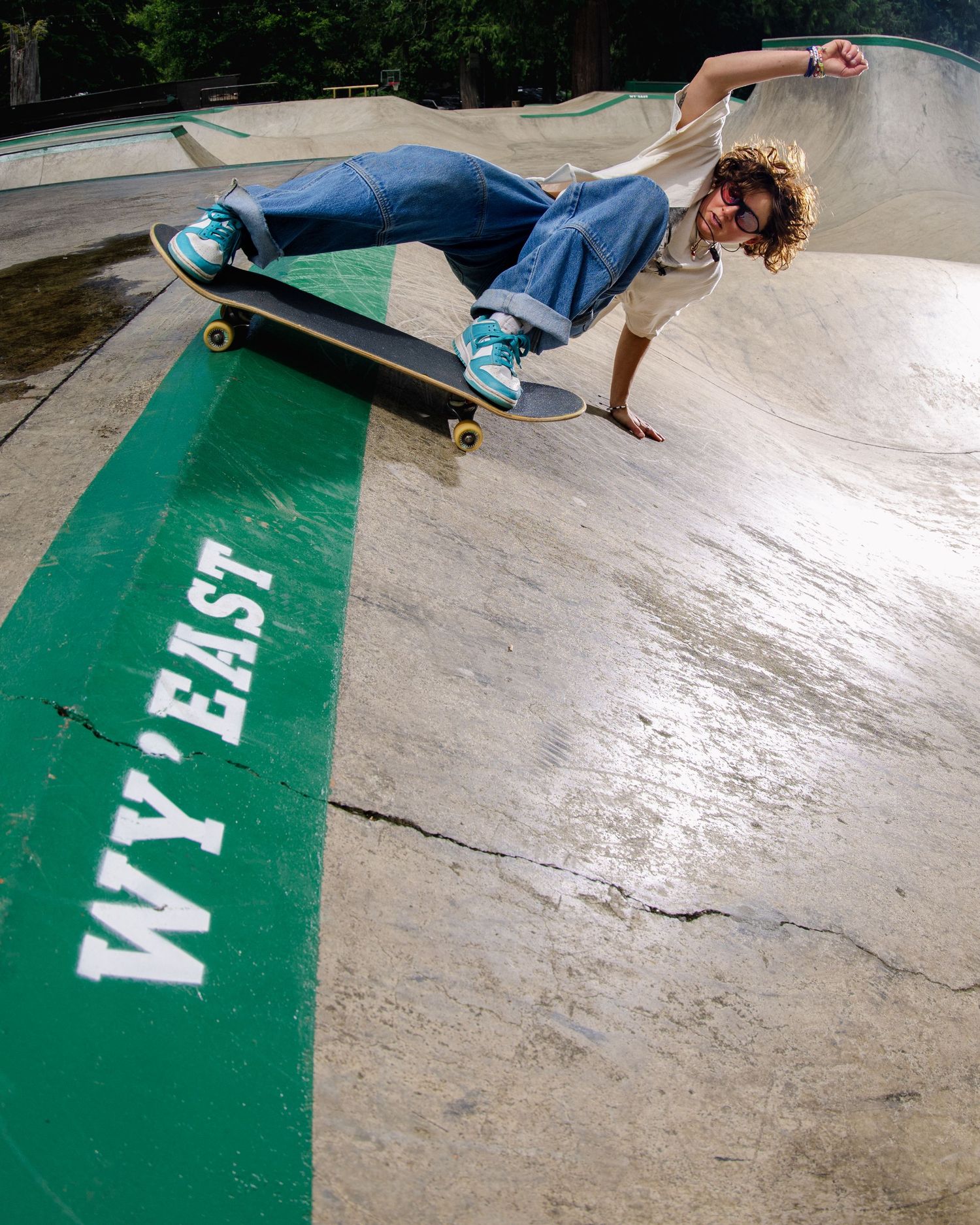 A skateboarder performs a handplant trick on a green-edged ramp at an outdoor skate park.