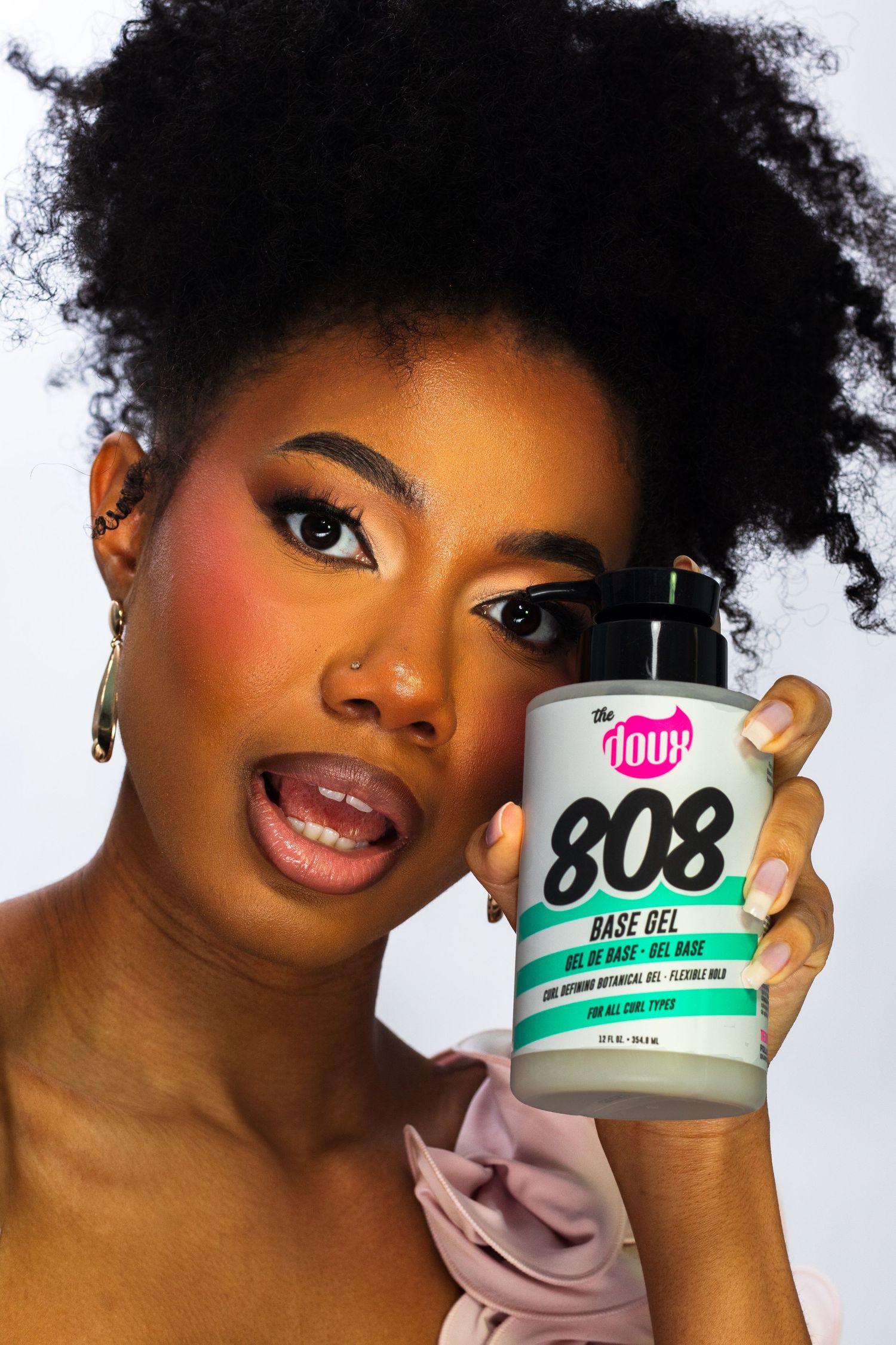 Woman holding The Doux 808 Base Gel hair product with excited expression.