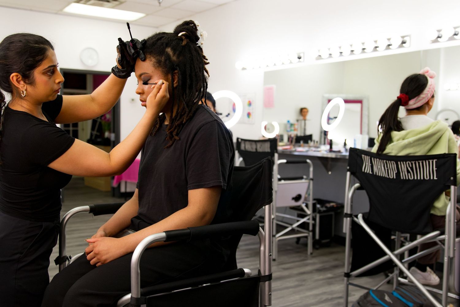 Makeup artist styling client hair at The Makeup Institute professional training studio.