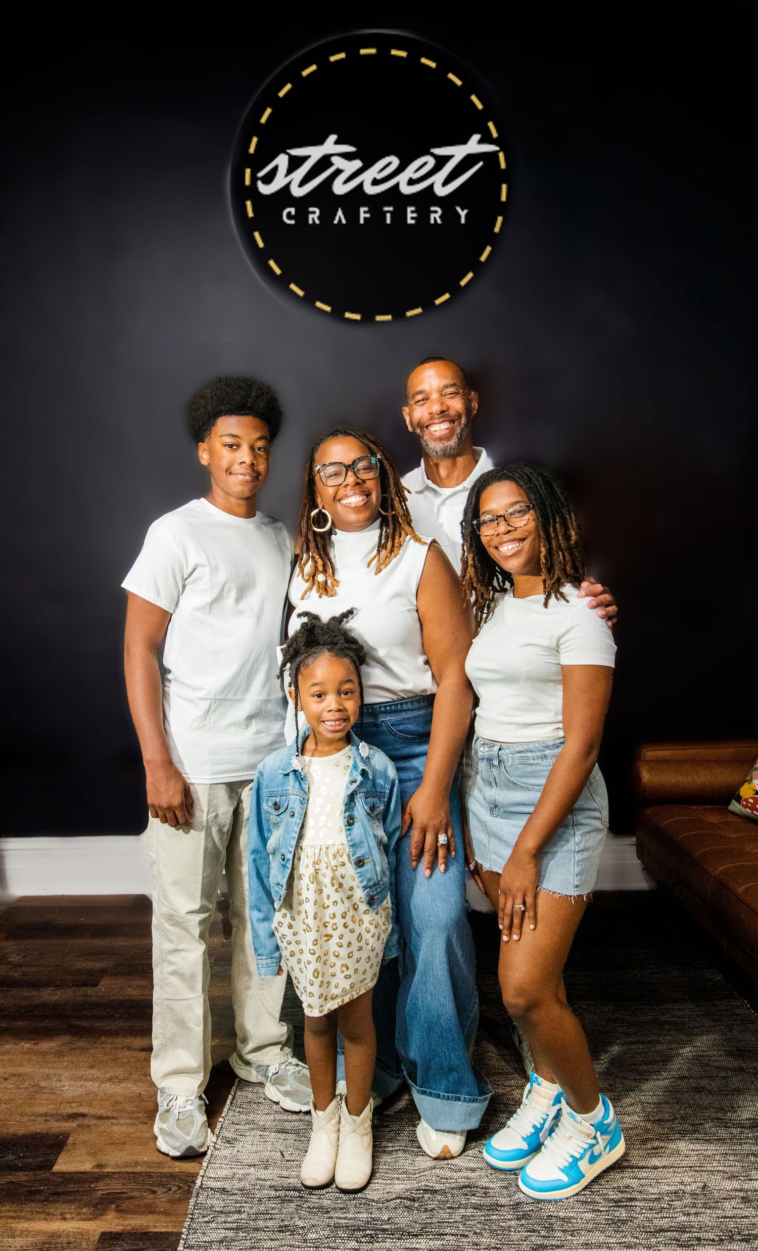 Family of five posing together in front of Street Craftery logo sign on a dark wall.