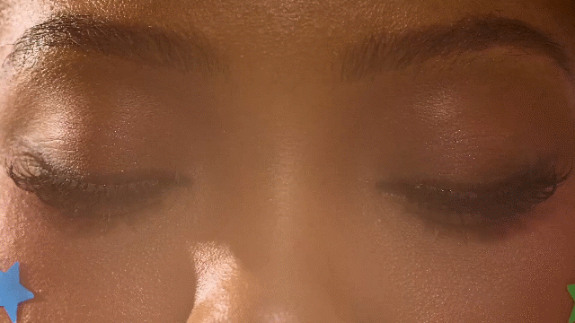 Extreme close-up of closed eyes with a blue star-shaped Starface pimple patch visible on cheek.