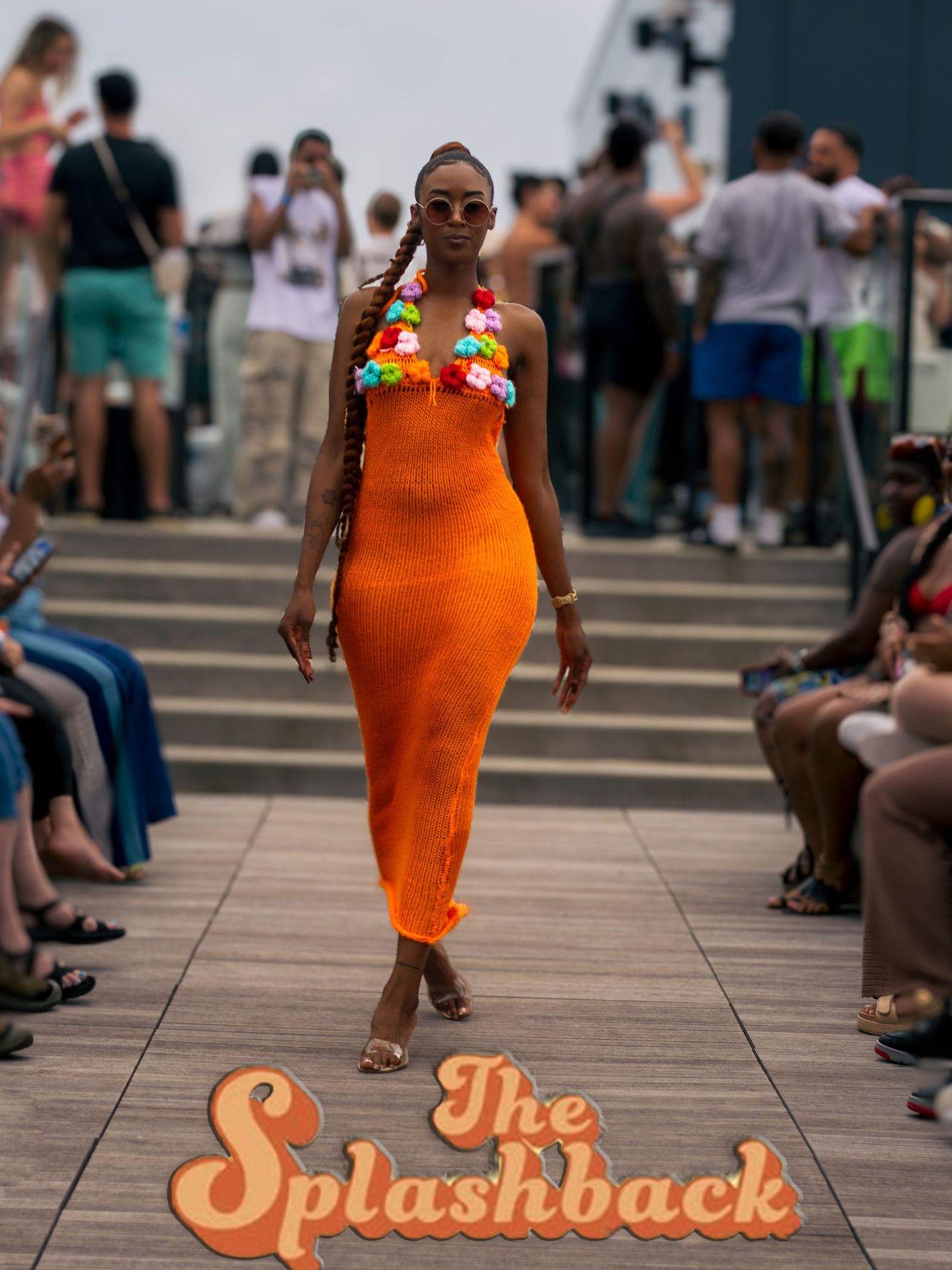 Model in orange knit dress walks The Splashback outdoor runway show on boardwalk.