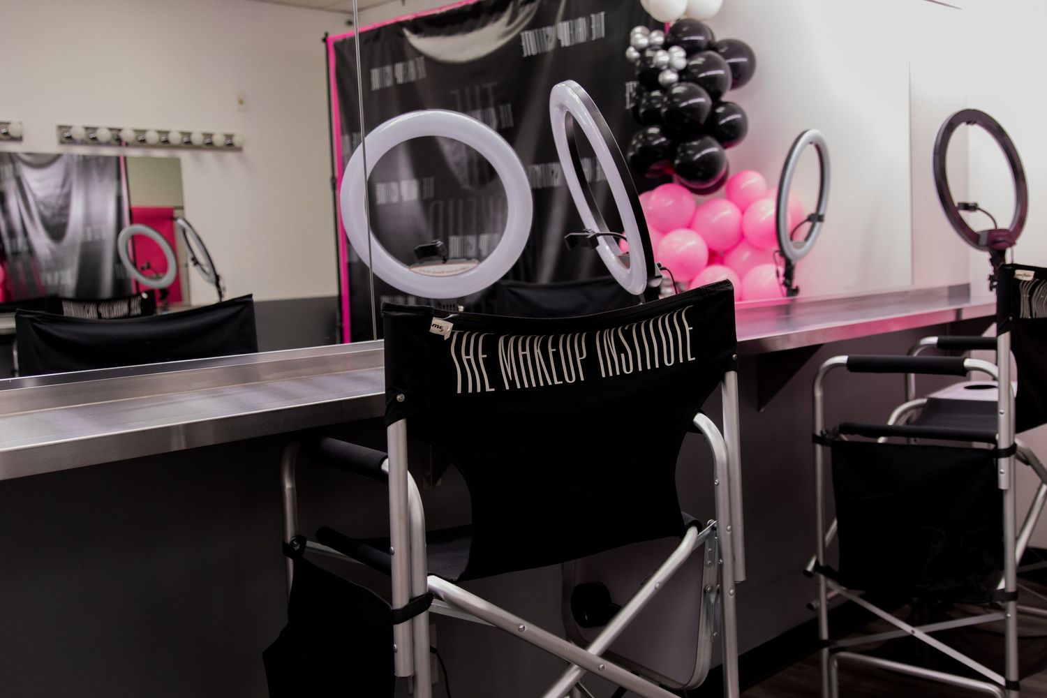 Close-up of The Makeup Institute branded director chair at professional makeup workstation with ring light.