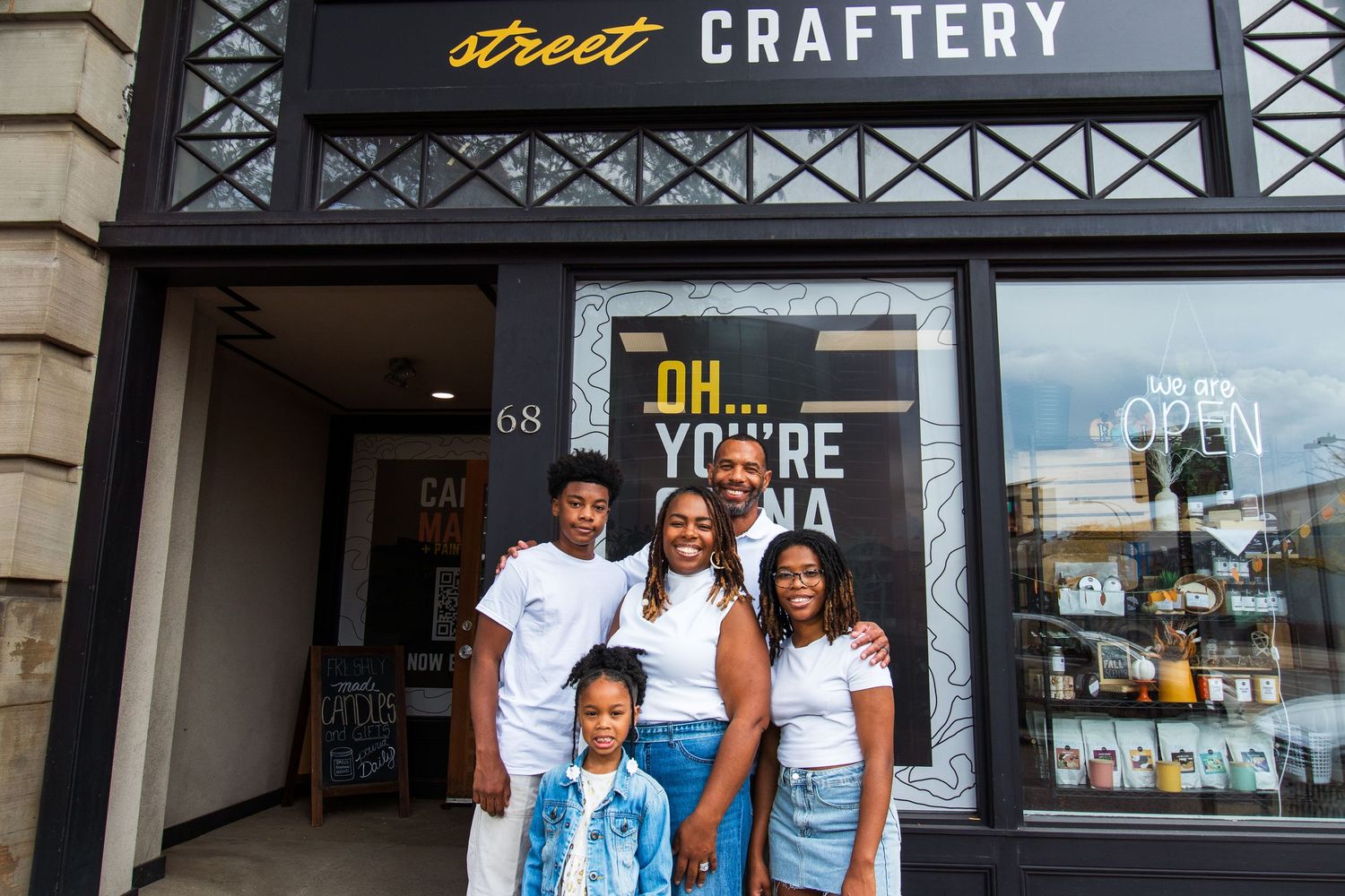 Family of four standing outside Street Craftery storefront at number 68 on a city street.