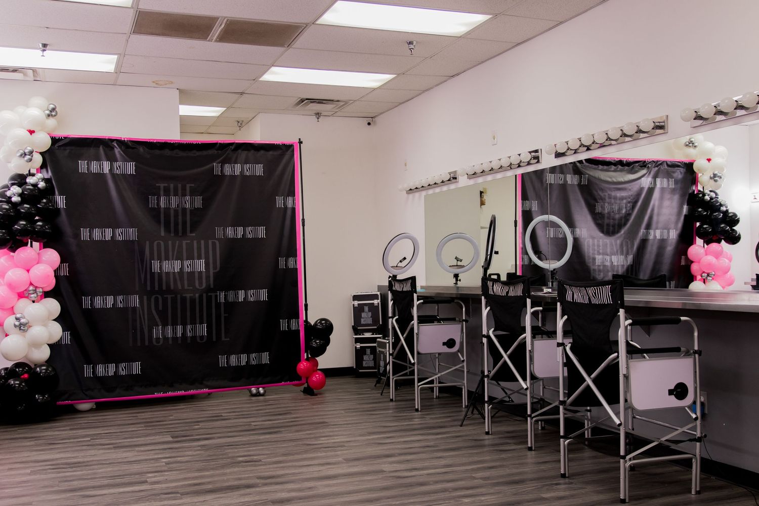 Makeup training studio featuring workstations with ring lights and decorative balloon columns.