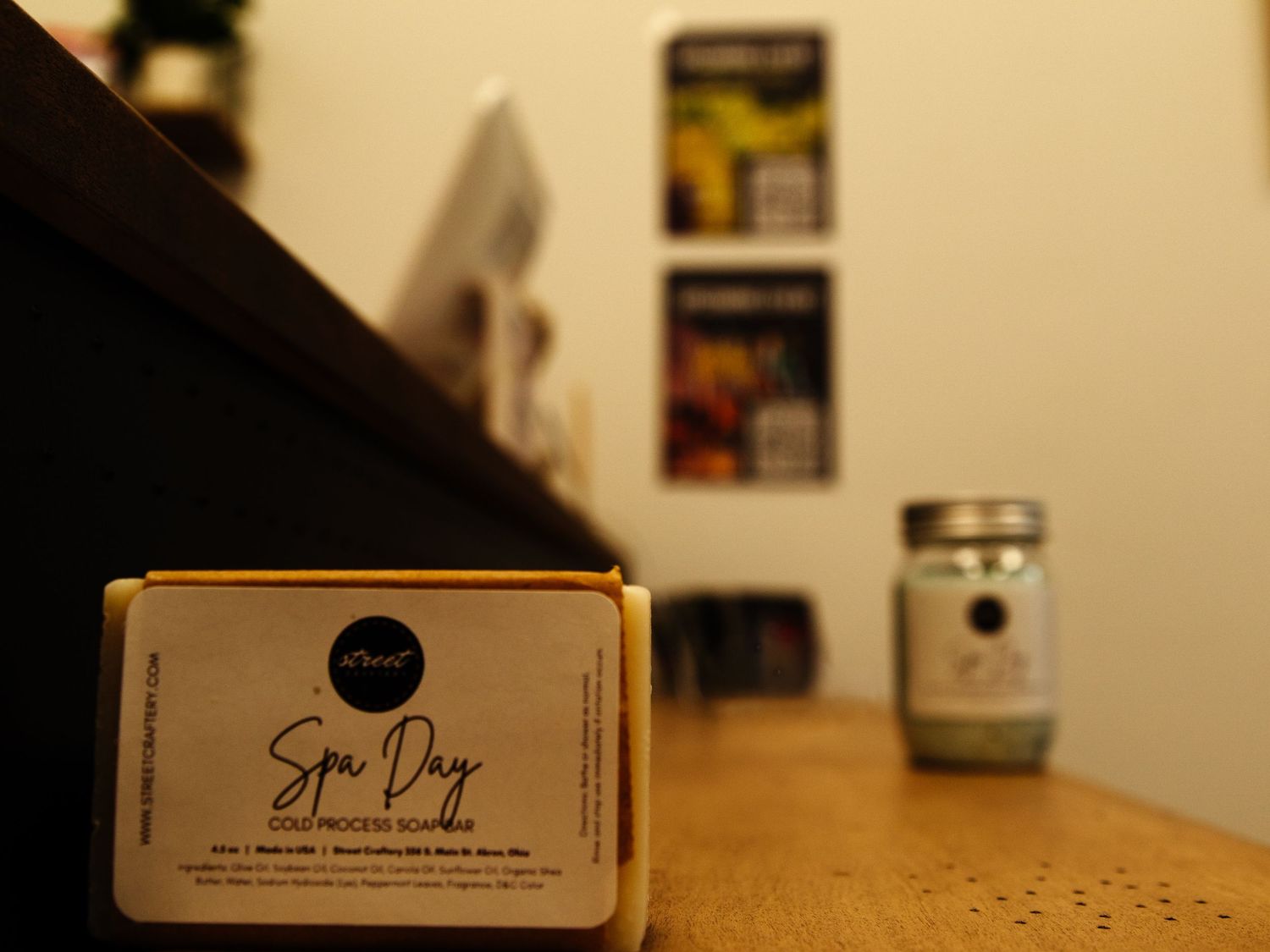 Spa Day cold process soap bar in gold packaging displayed on wooden surface with blurred jar in background.