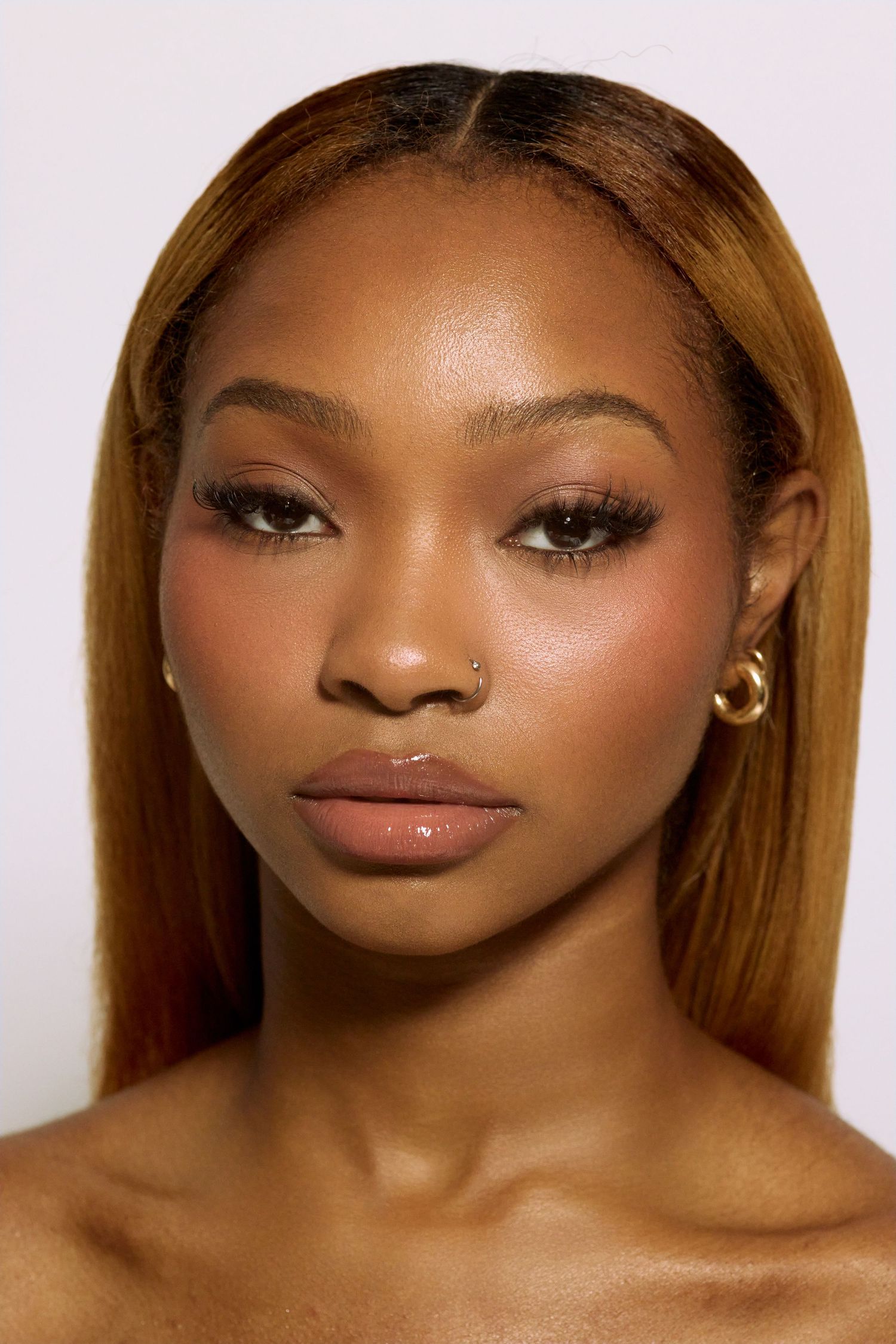 Close portrait of a young woman with ombre hair, nose ring, and gold hoop earrings.