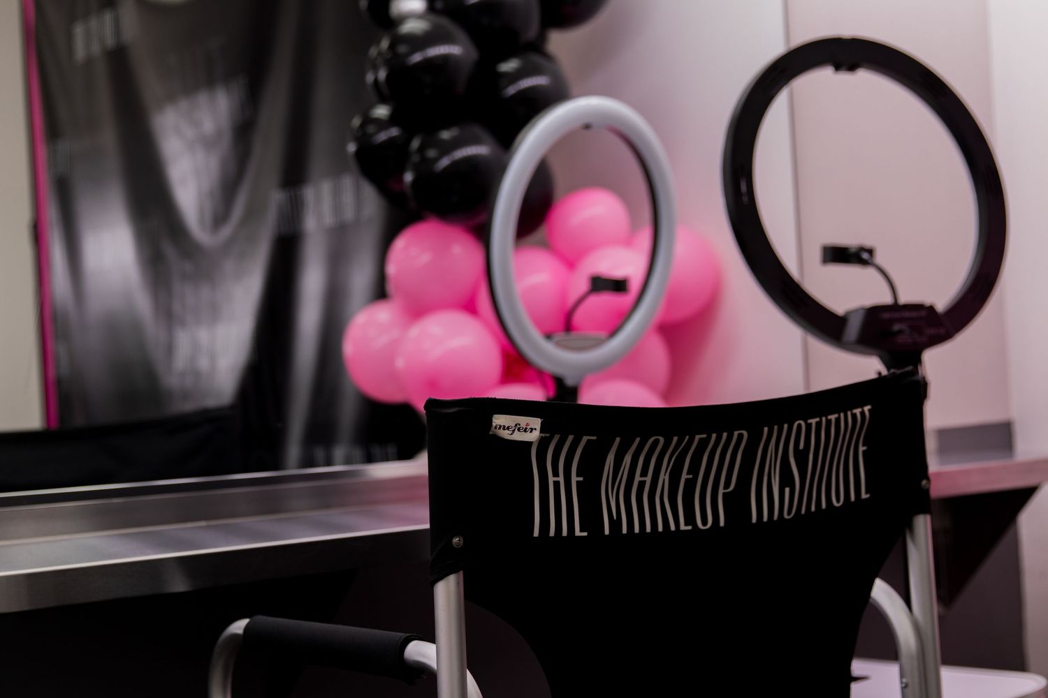 The Makeup Institute director chair with ring light and pink black balloon decor in studio.