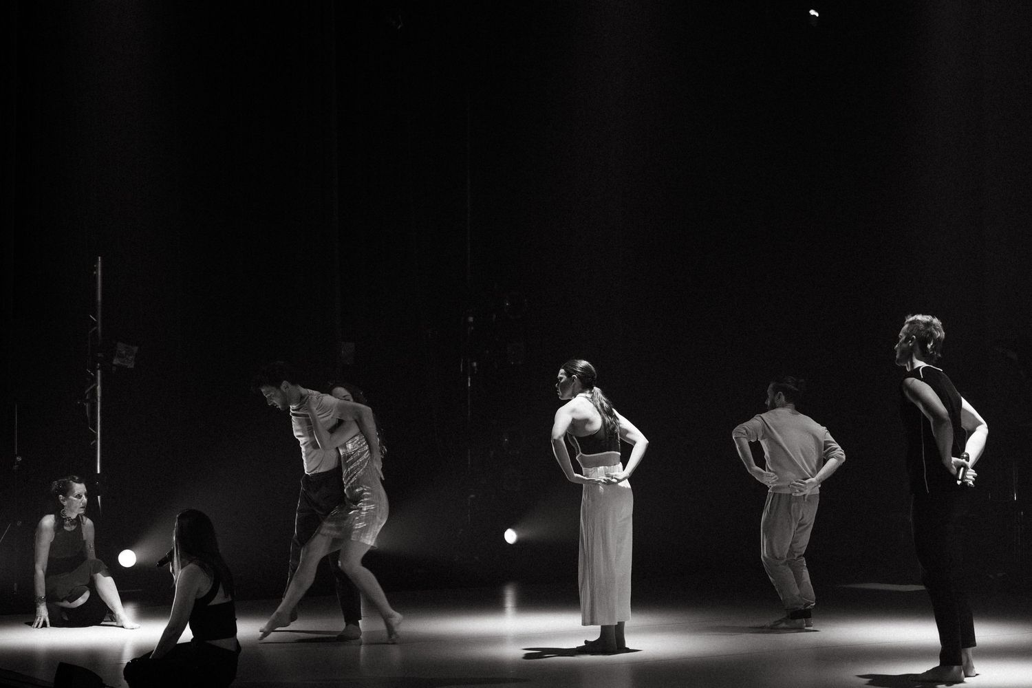Dramatic black and white images of performers on stage during a modern contemporary dance performance in a dark theater.
