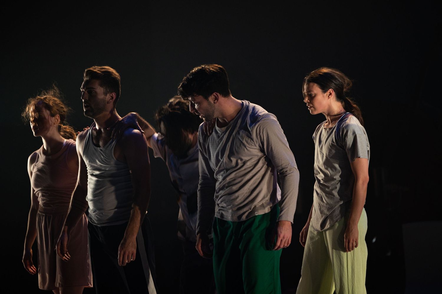 People performing on a dark stage with dramatic lighting effects during a theatrical production.