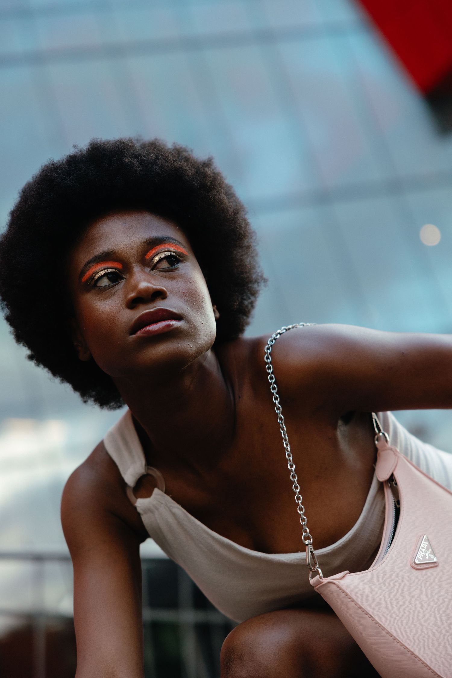Portrait of a person with natural afro hair wearing a beige athletic tank top and silver chain in warm evening light.