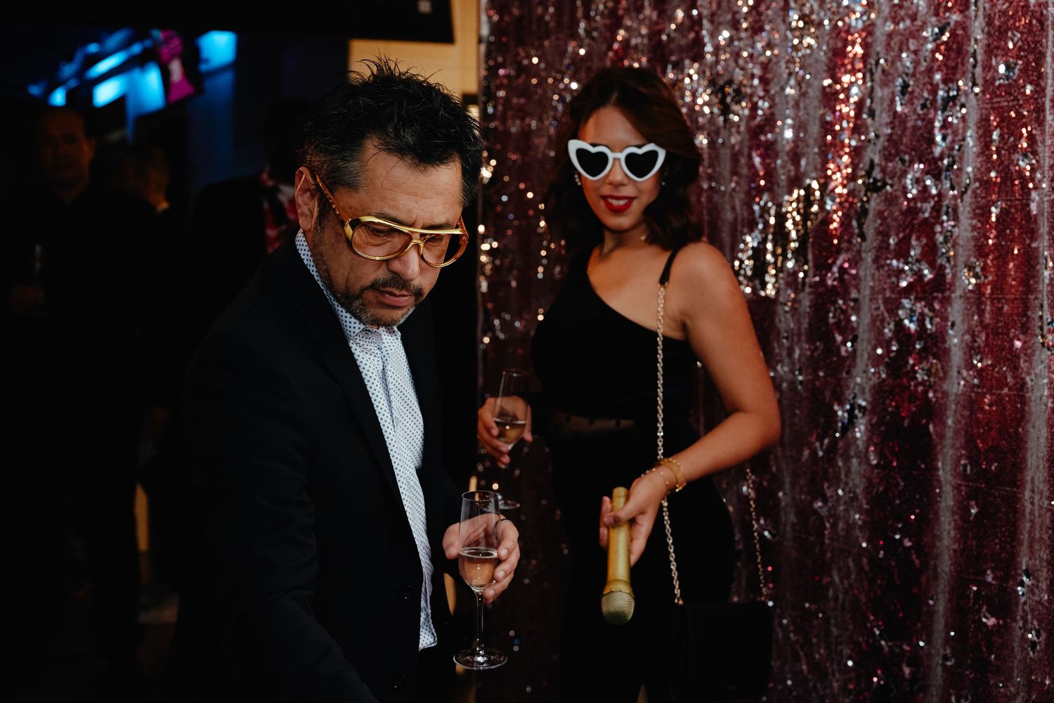 A group of people in formal attire enjoying a party under sparkling red decorative tinsel and lights at an event.