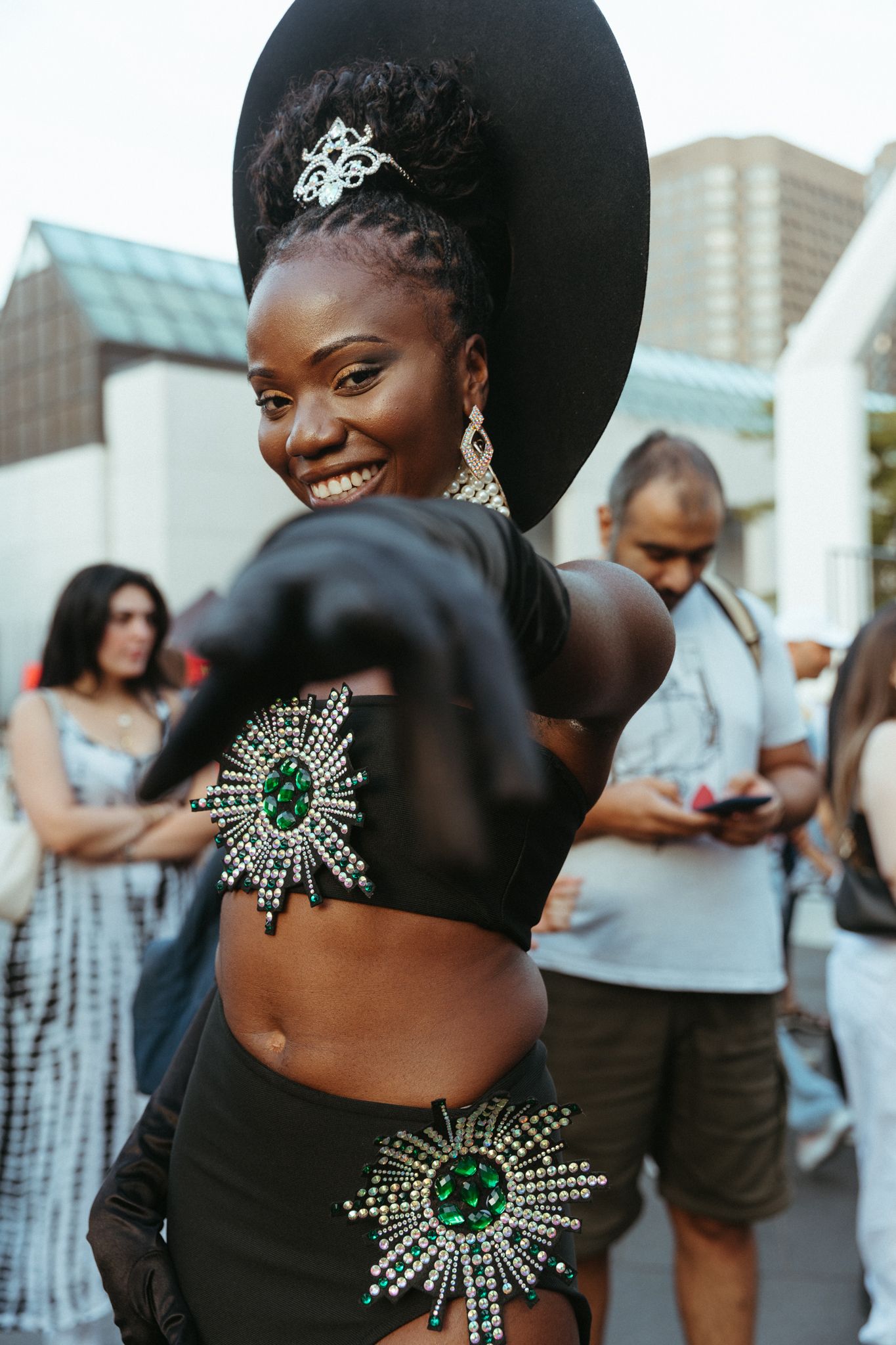 Glamorous attendee at an event wearing a black outfit with emerald green starburst brooches and elegant accessories.