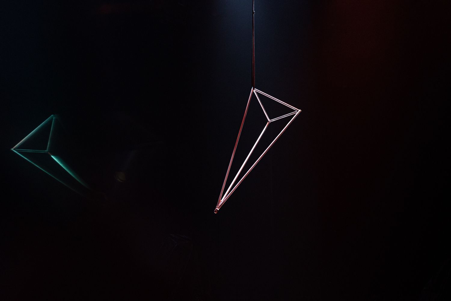 Series of abstract triangular shapes and lines glowing against a black background.