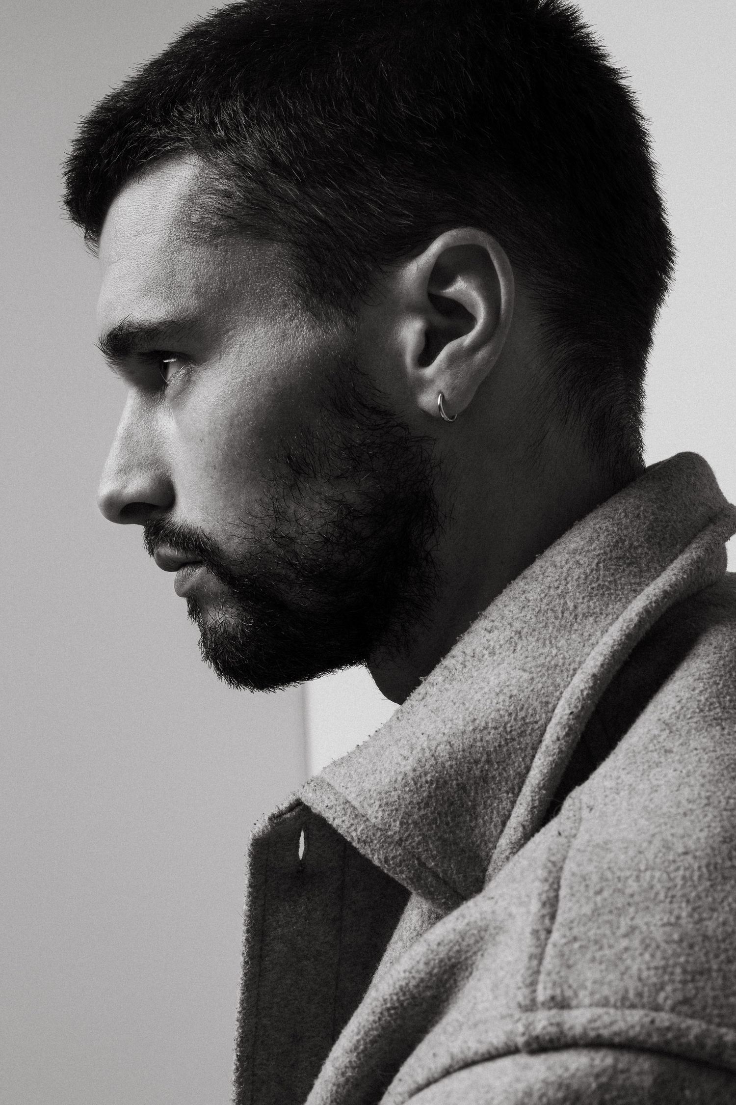 Side profile portrait in black and white showcasing a well-groomed beard against a light backdrop.