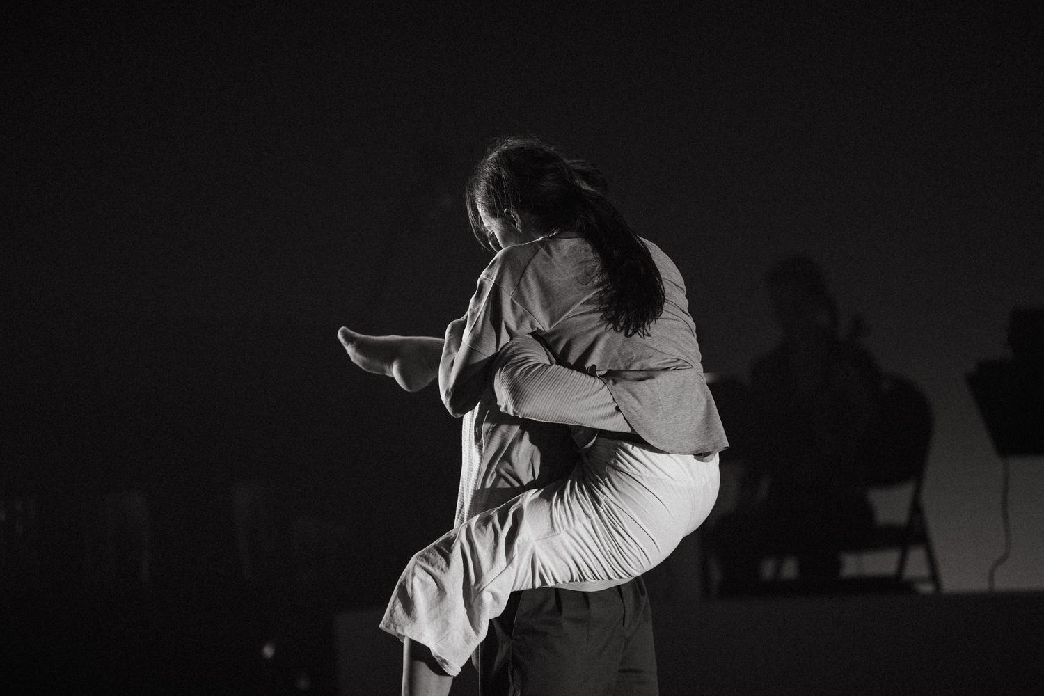 Black and white photo series showing a couple embracing during what appears to be a modern dance performance.