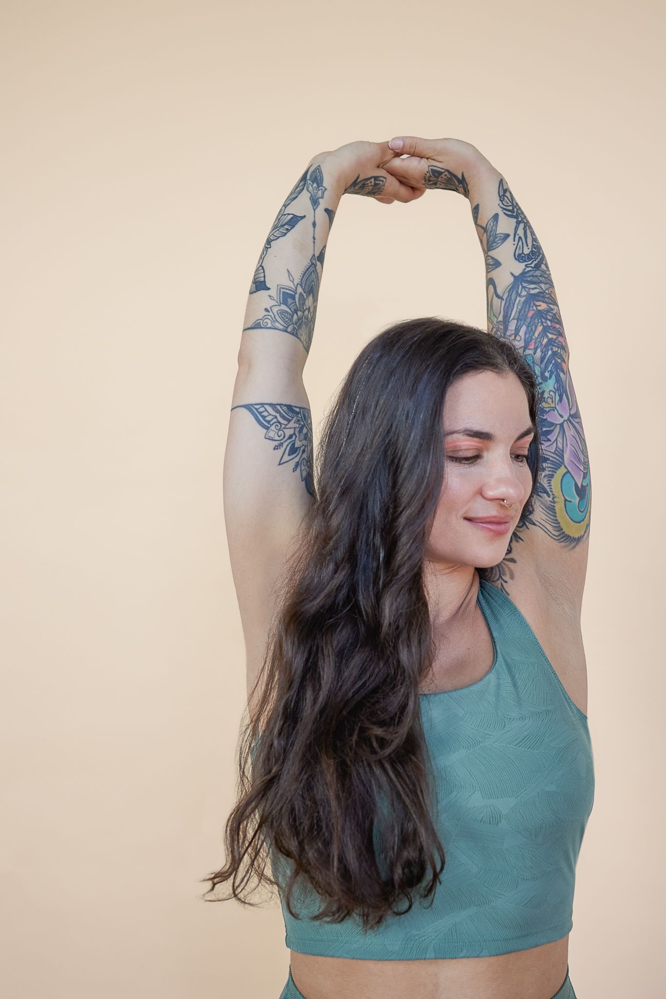 A person with long dark hair wearing a teal top poses against a beige background in a sequence of expressive movements.