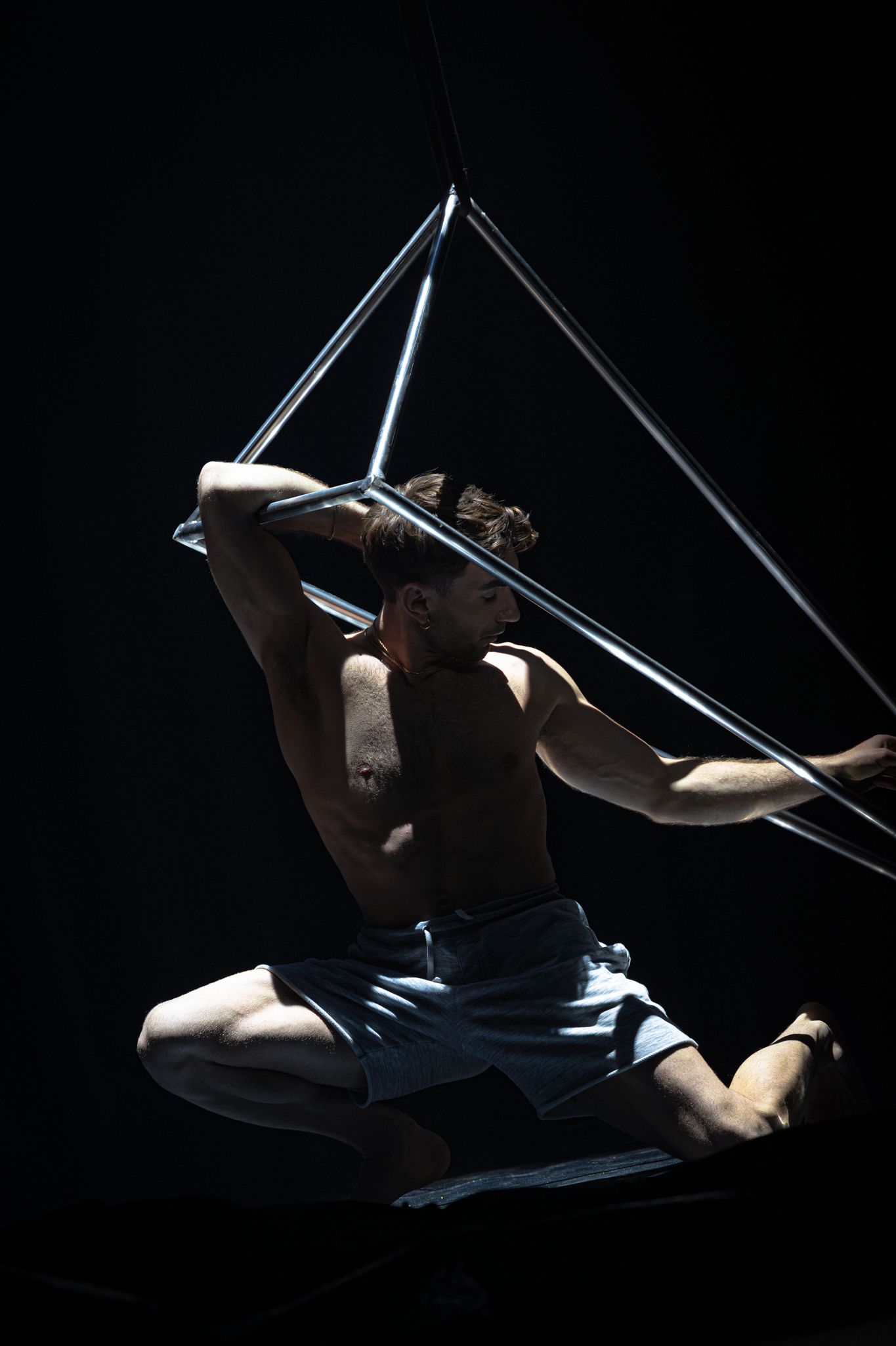 A dramatic aerial dance performance silhouetted against a dark background showing graceful acrobatic movements in sequence.