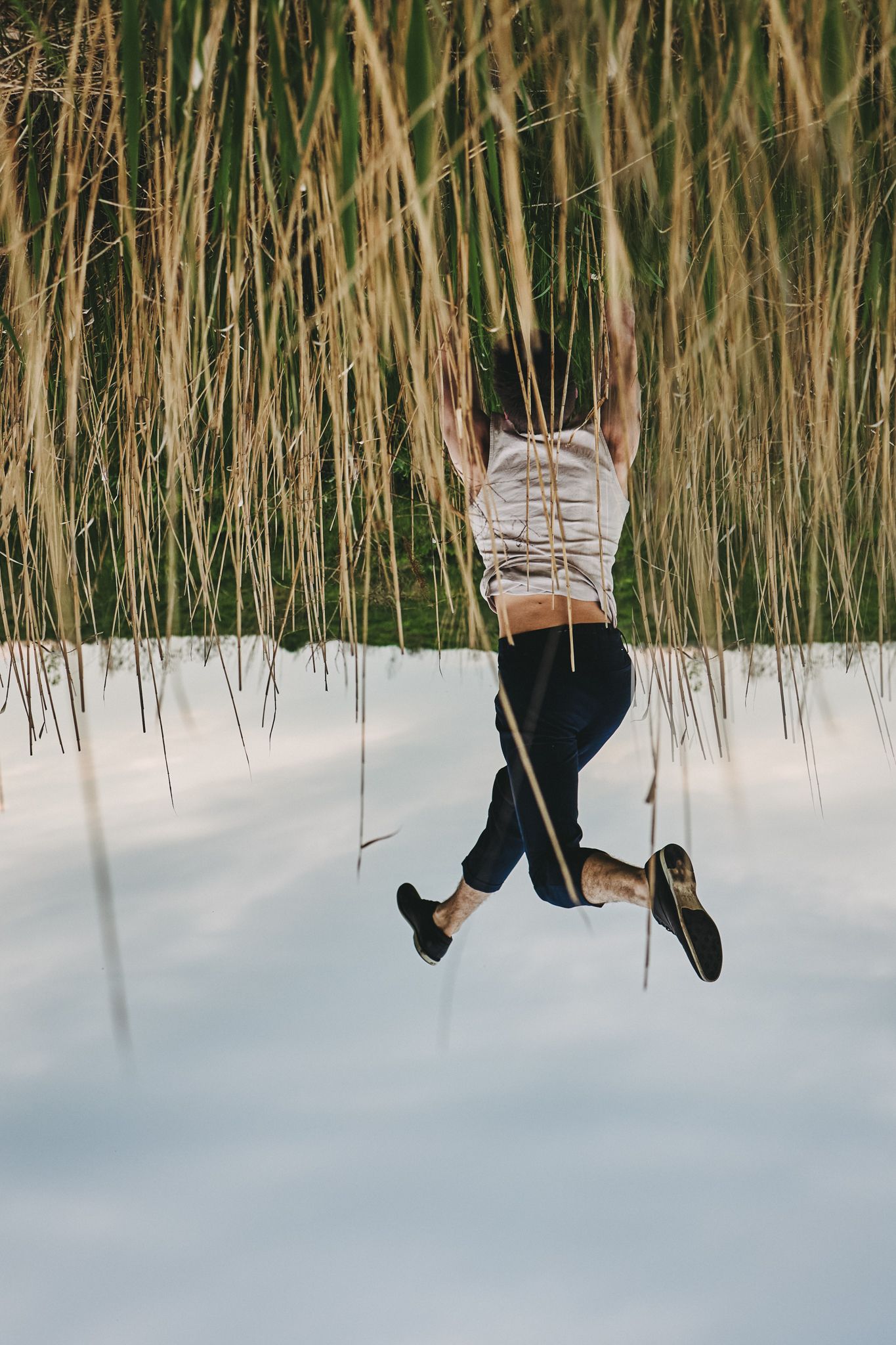 Boots and legs swinging playfully against a winter snow background framed by golden dried grass.